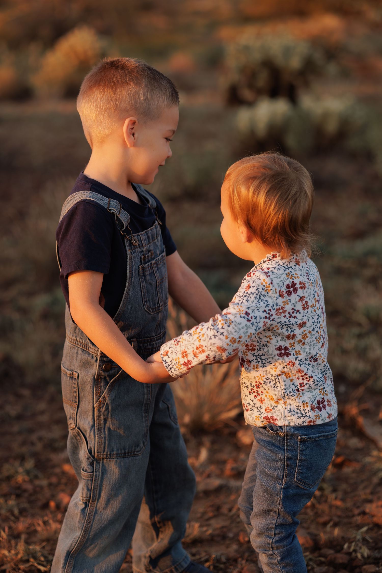 Two young children in denim playing together at sunset.