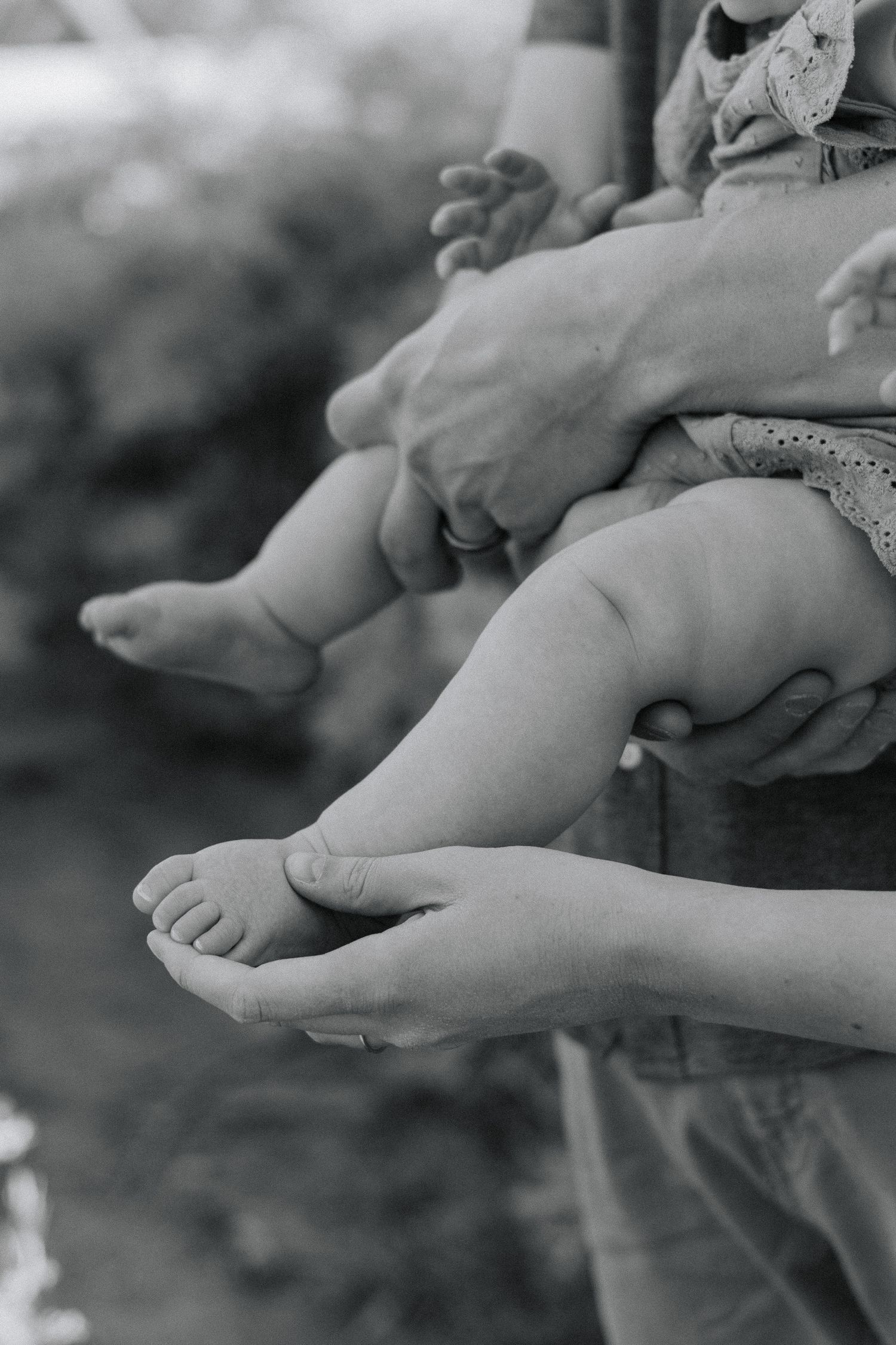 Black and white close-up of bare feet being tenderly touched.