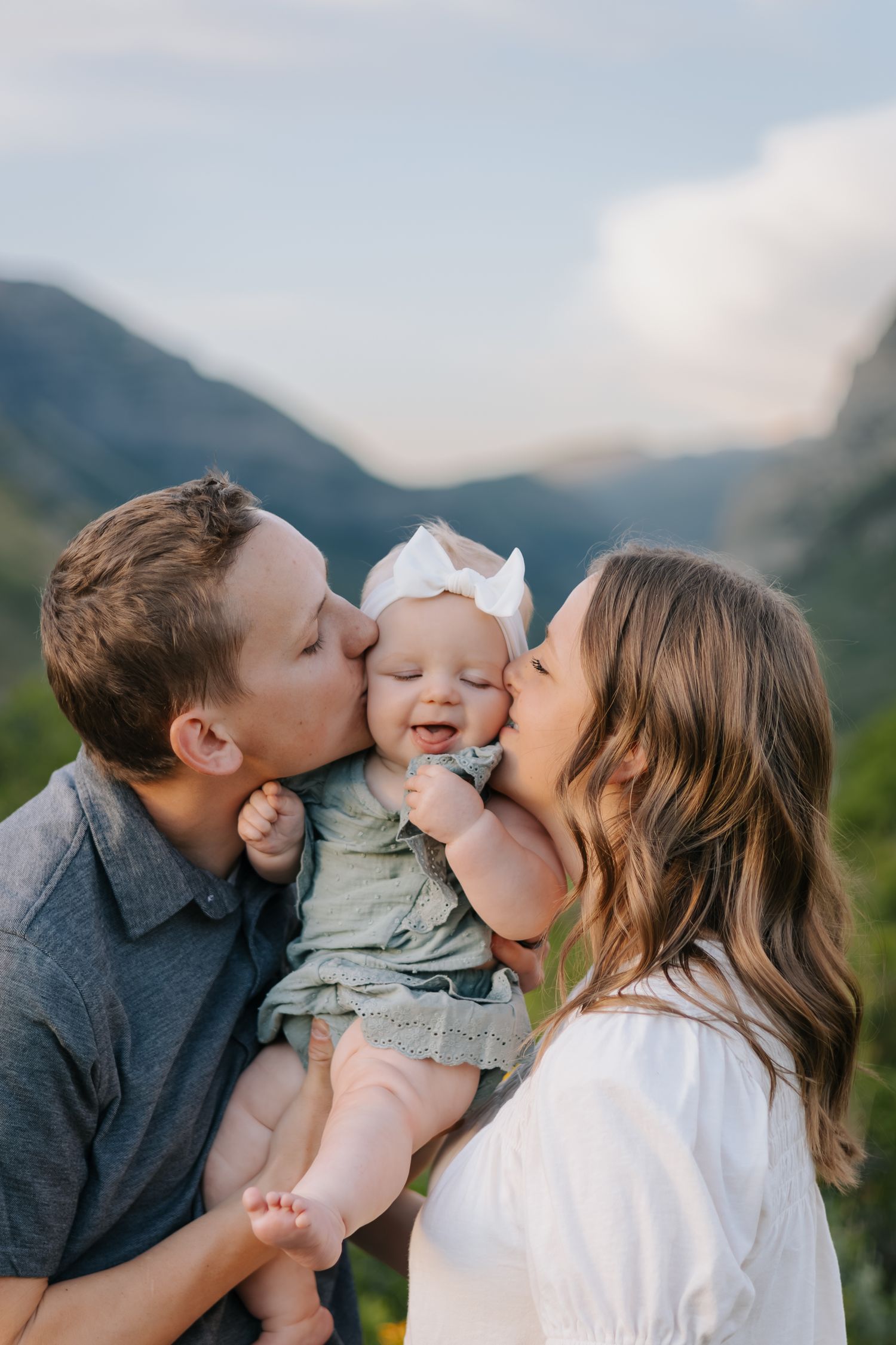 A sweet family moment shared outdoors with mountain scenery in the background.