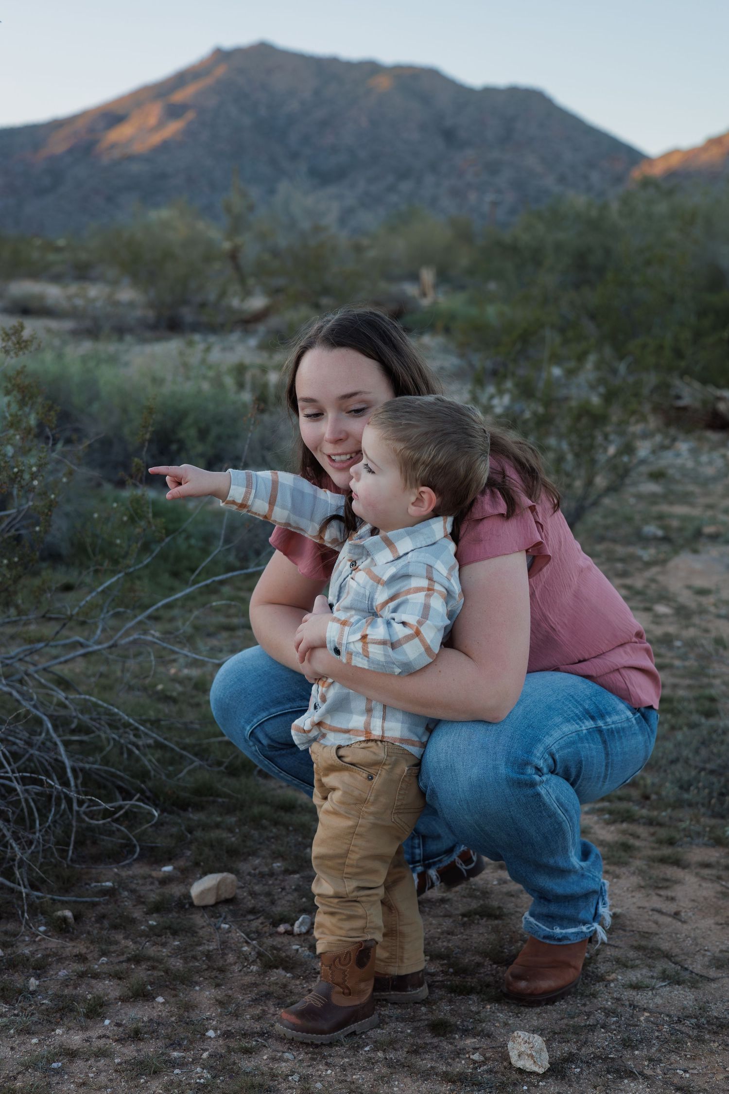 Parent and child sharing a tender moment against desert mountain backdrop at dusk.