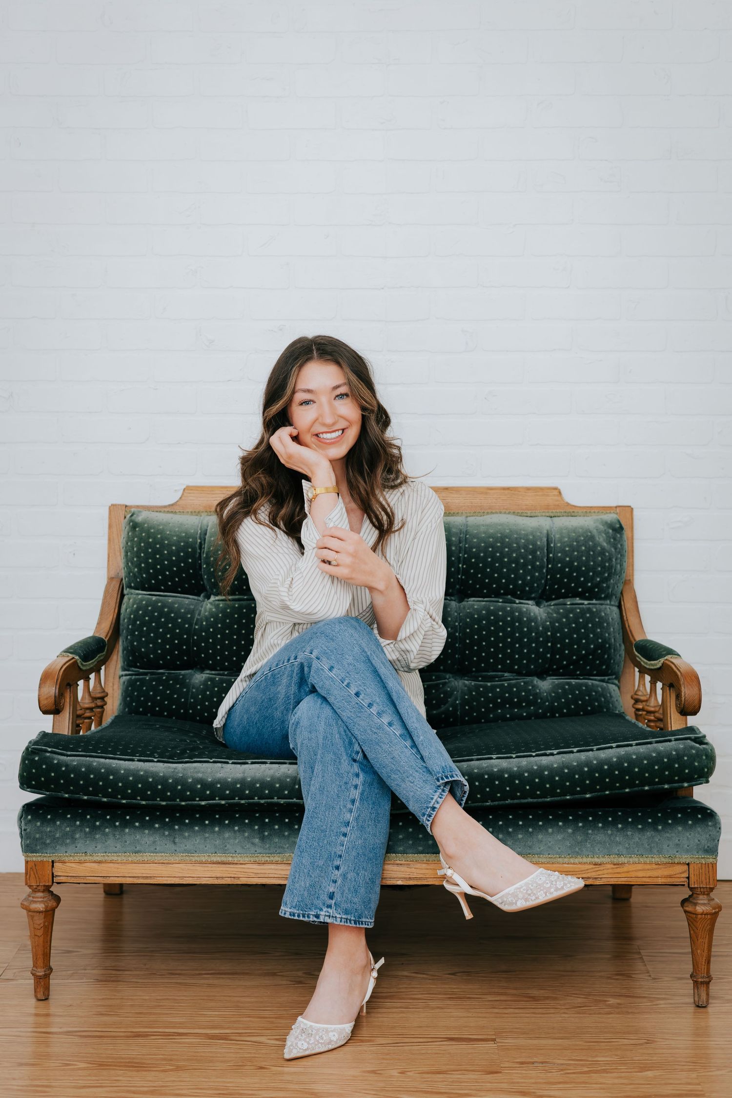 Someone posing on a vintage blue velvet couch in casual denim and white top.