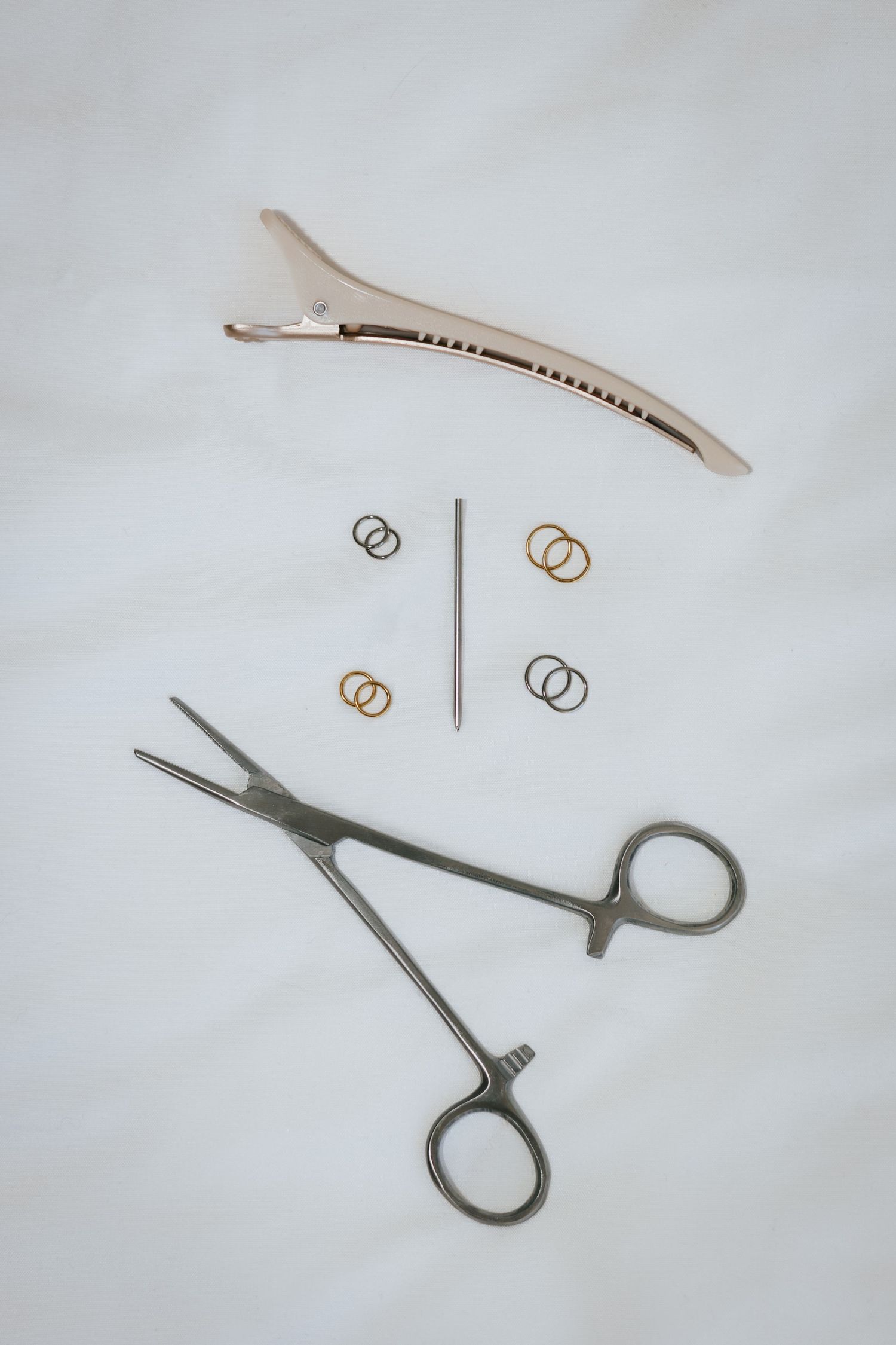 Various pieces of jewelry and tools including scissors and rings arranged on a white surface.