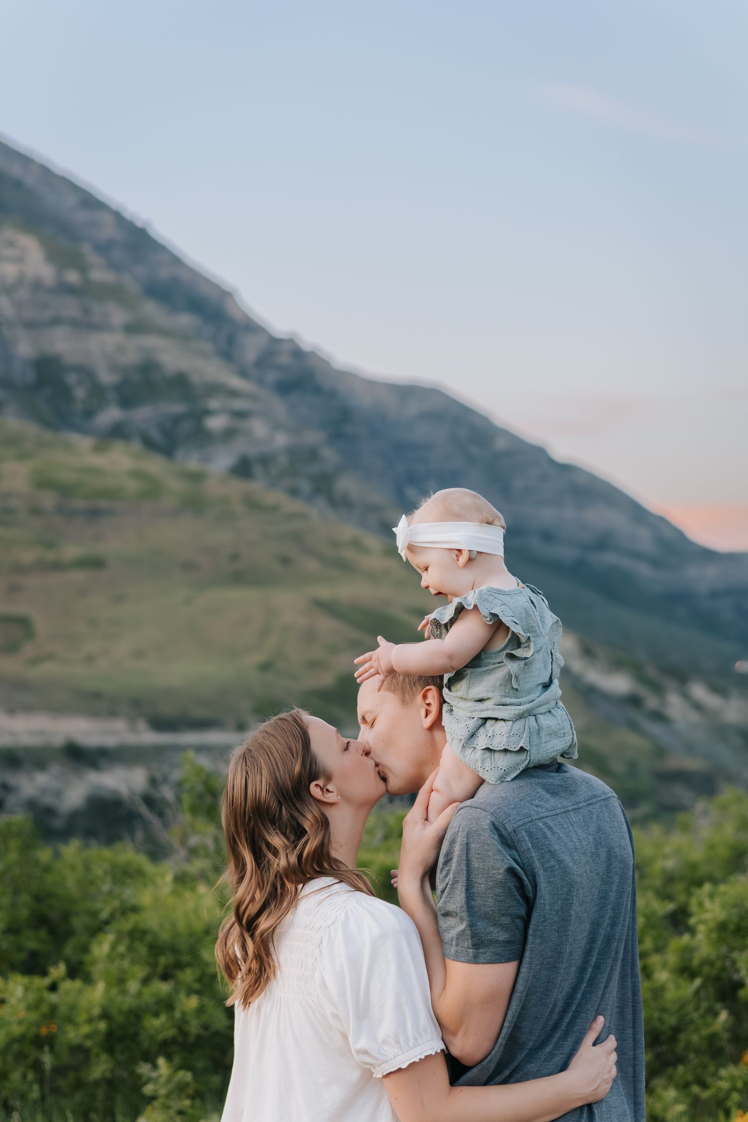 A family embraces while silhouetted against a mountainous landscape at sunset.