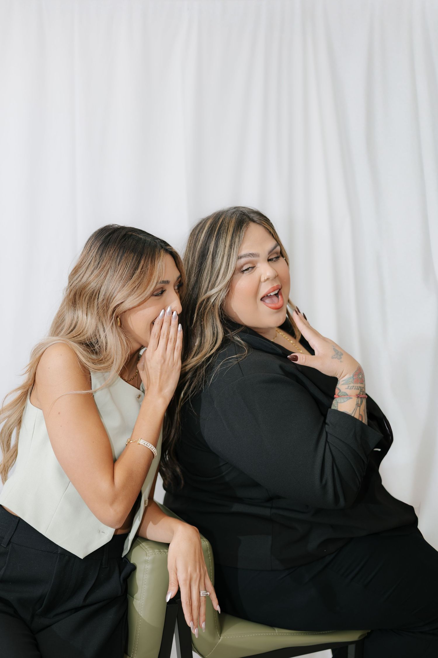 Two friends sharing secrets and laughing together during a casual photoshoot.