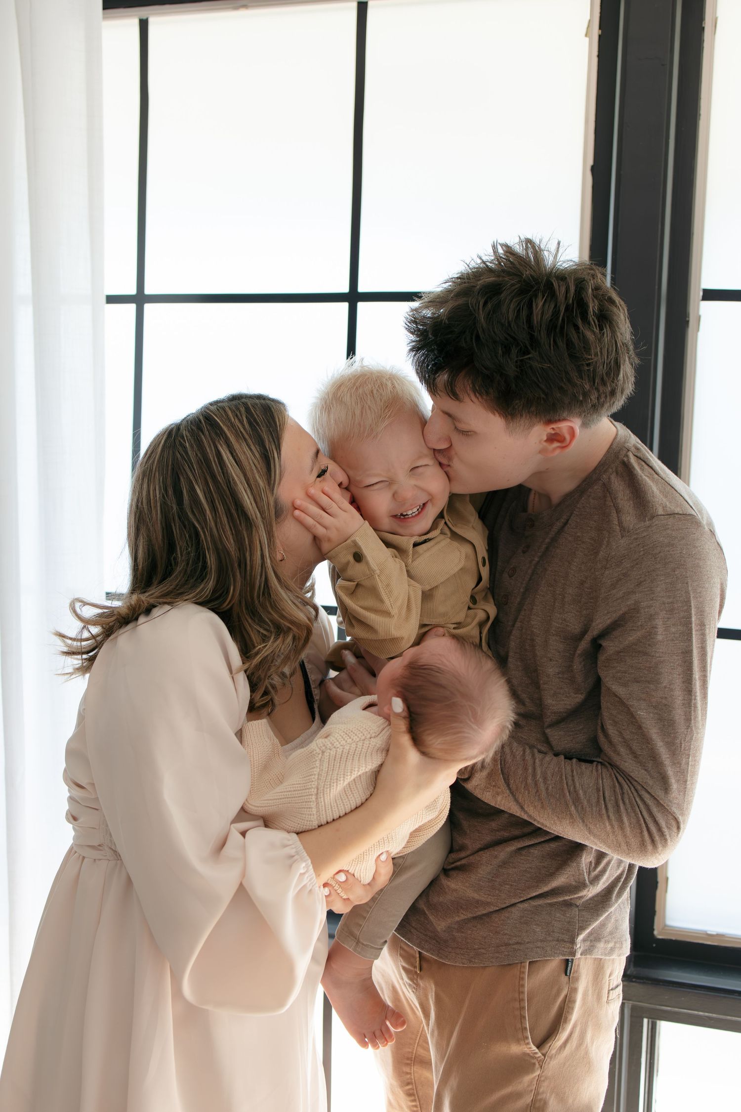Tender family moment by a window in soft natural light.