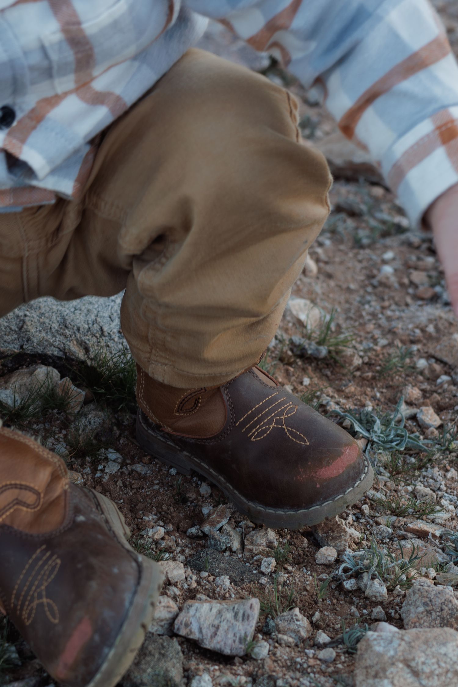 Close-up of brown hiking boots on rocky mountain terrain.