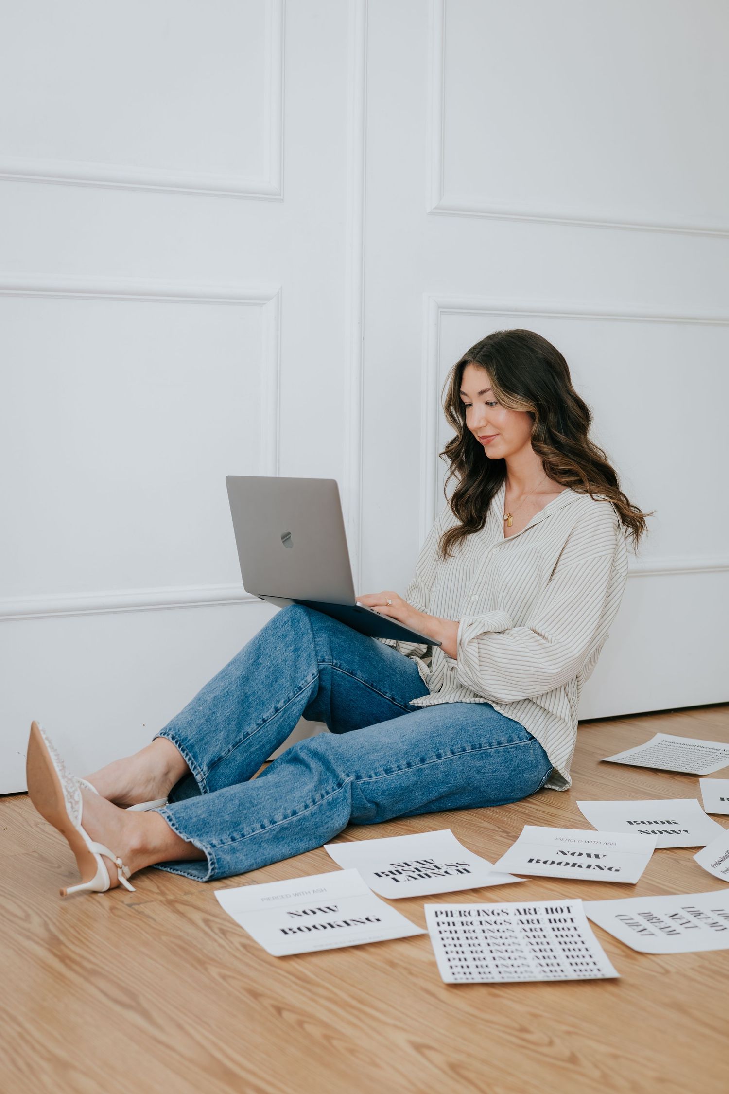Someone lying on wooden floor with laptop and paper cards scattered around.