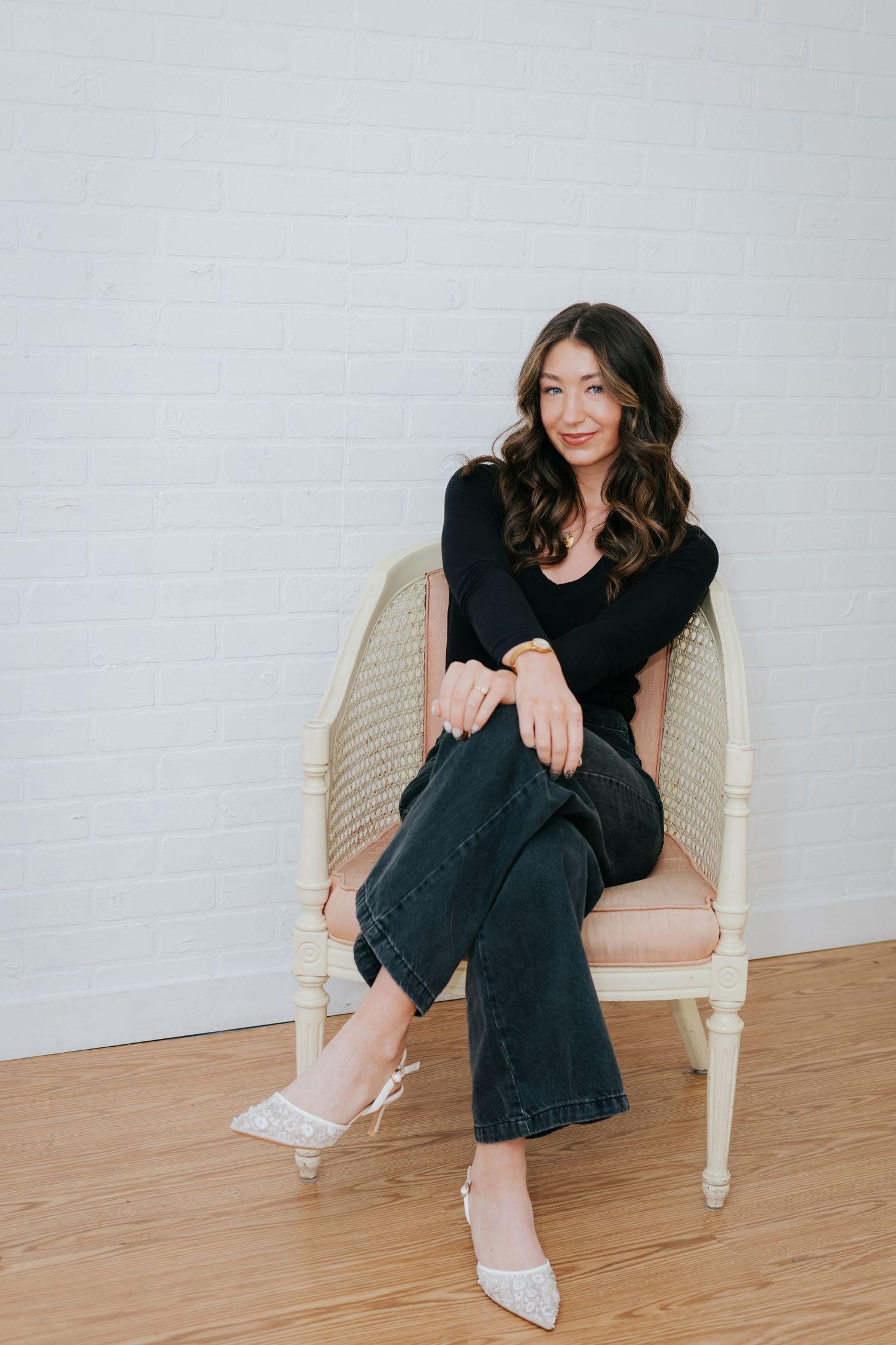 Someone lounging in a cream-colored chair wearing dark denim and a black top.