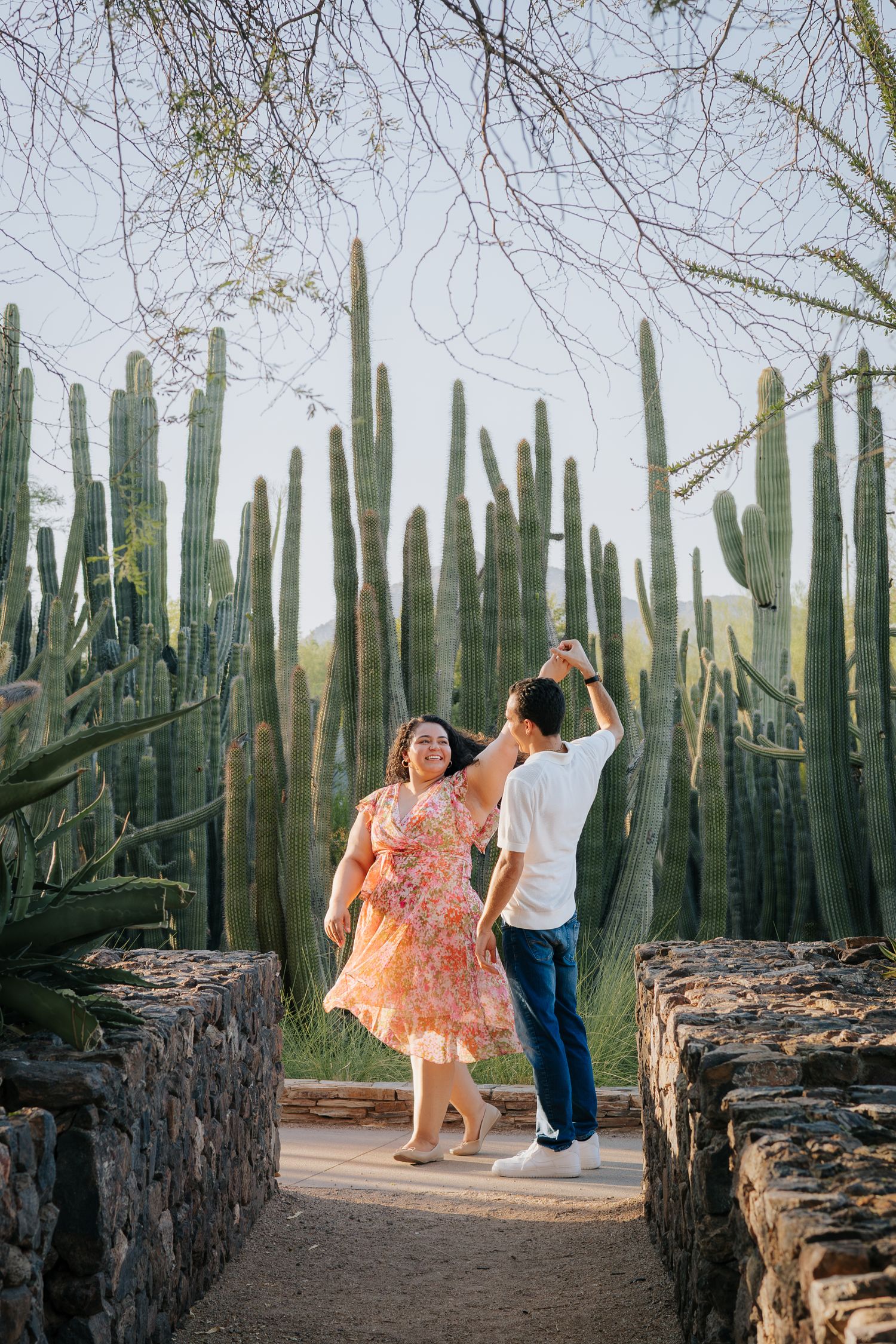 Couple dances together in a desert garden surrounded by tall cactus plants.