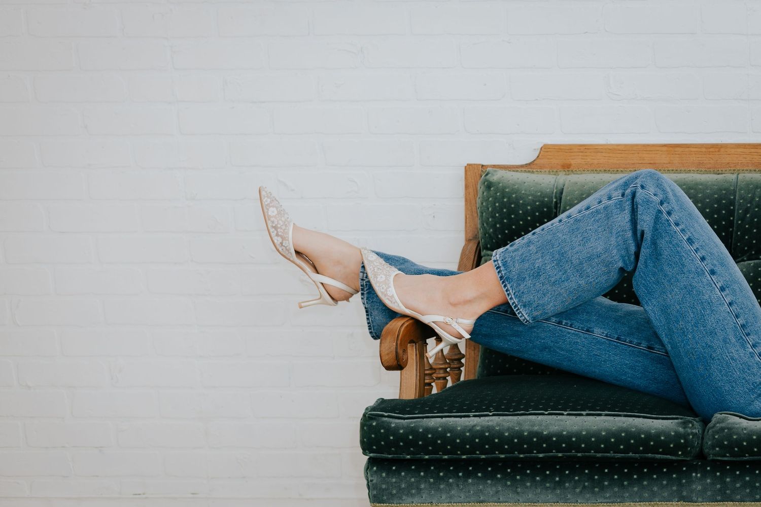 Close up view of someone lounging on a blue velvet vintage couch.
