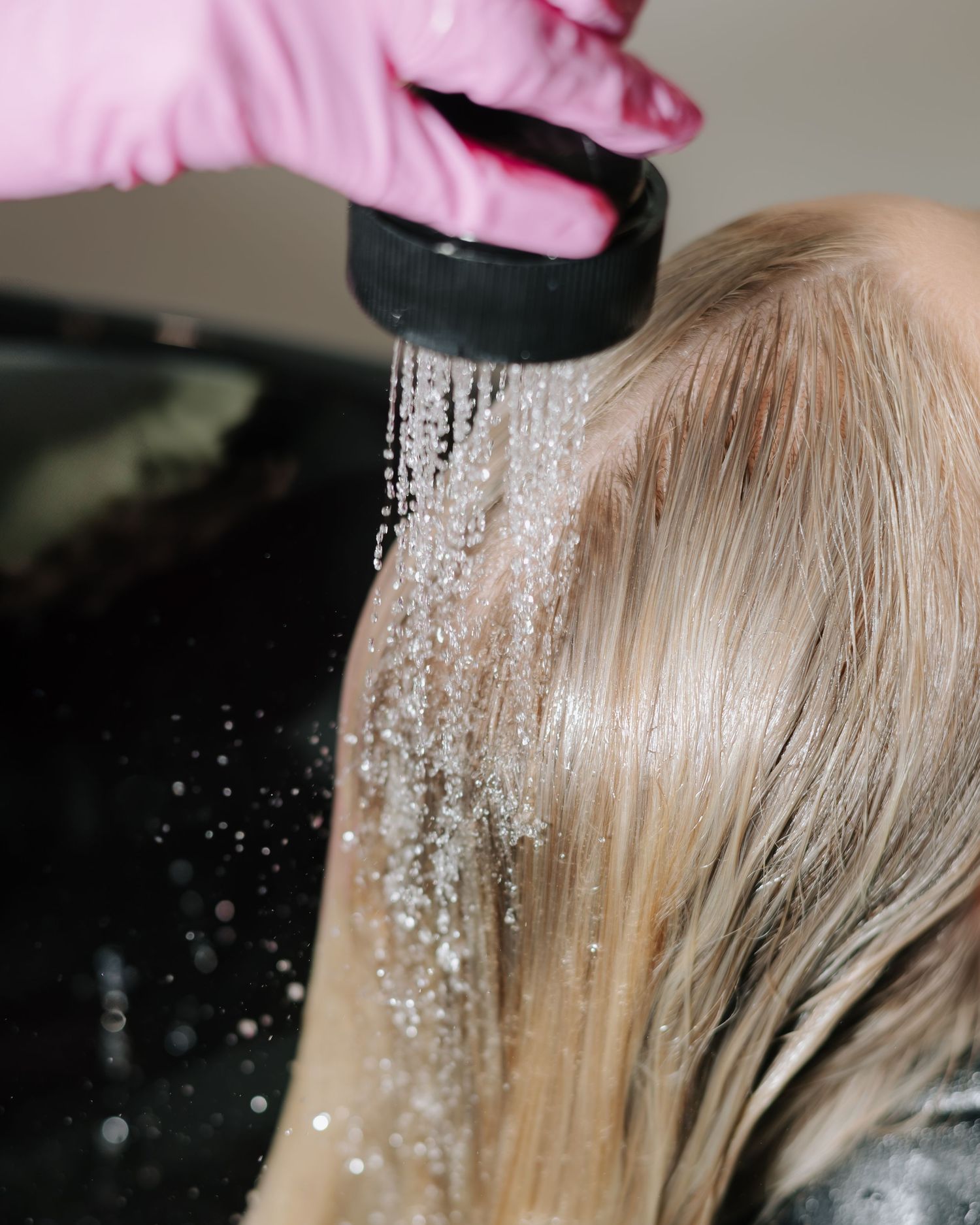 Close-up of hair bleaching process showing powder being sprinkled on blonde hair.