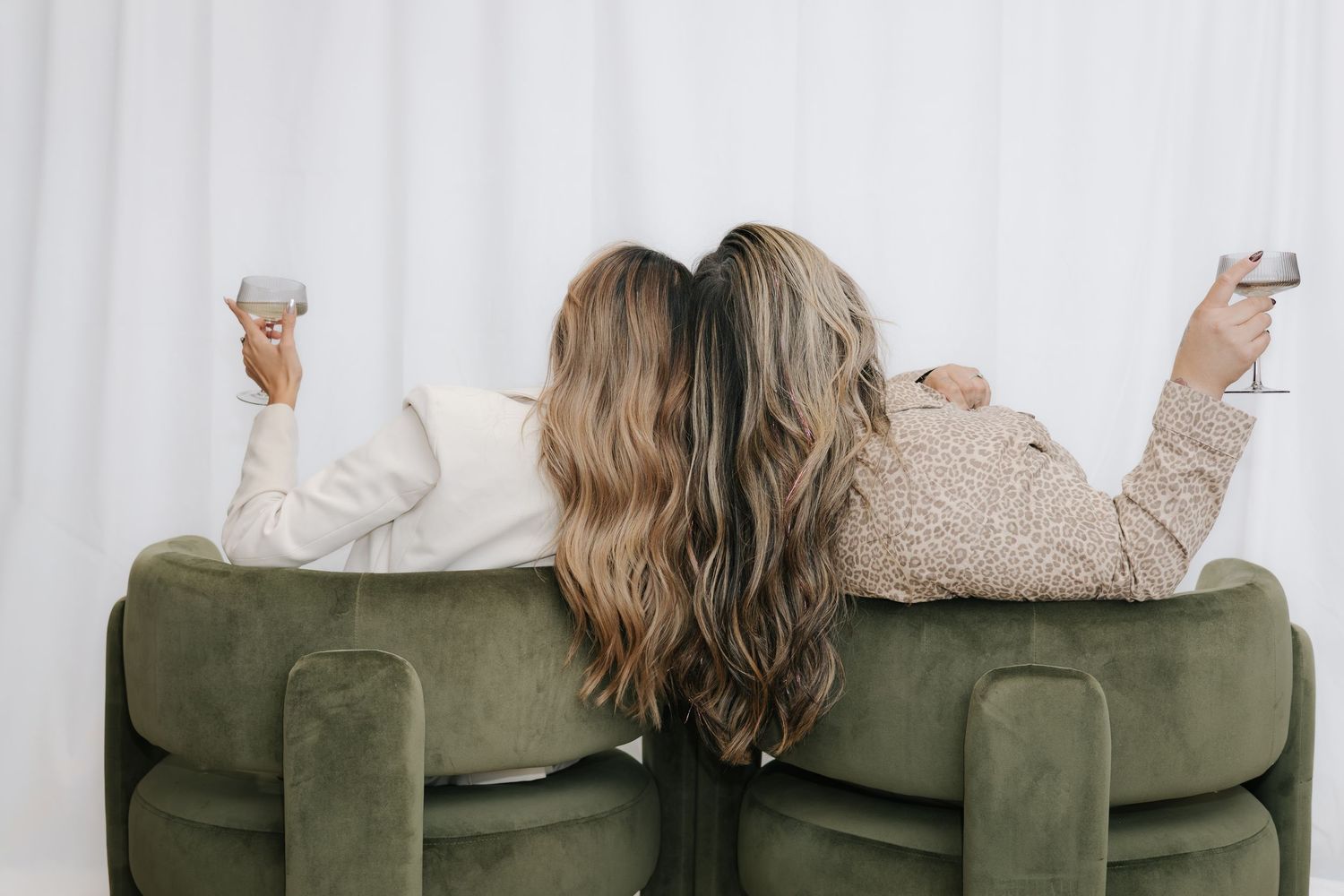 Friends relaxing on olive green couch during casual photoshoot session.
