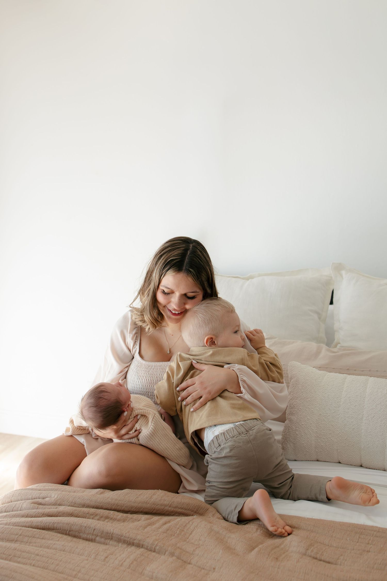 Mother and children sharing intimate moment on white bedding.
