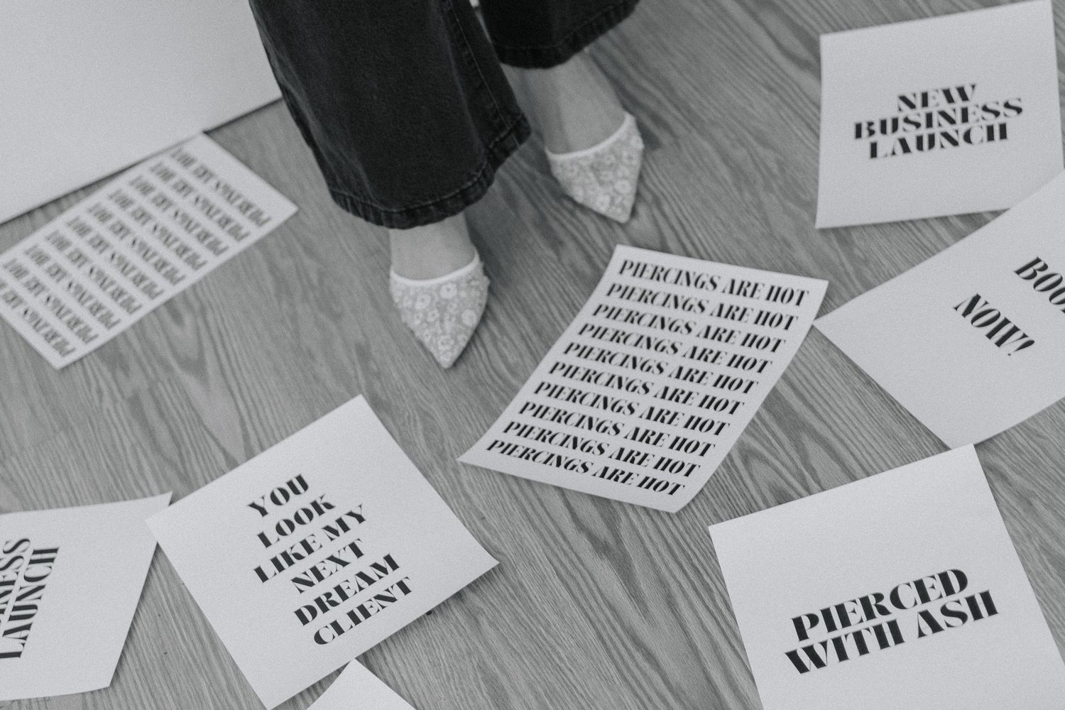 Black and white image of scattered text cards on a wooden floor.