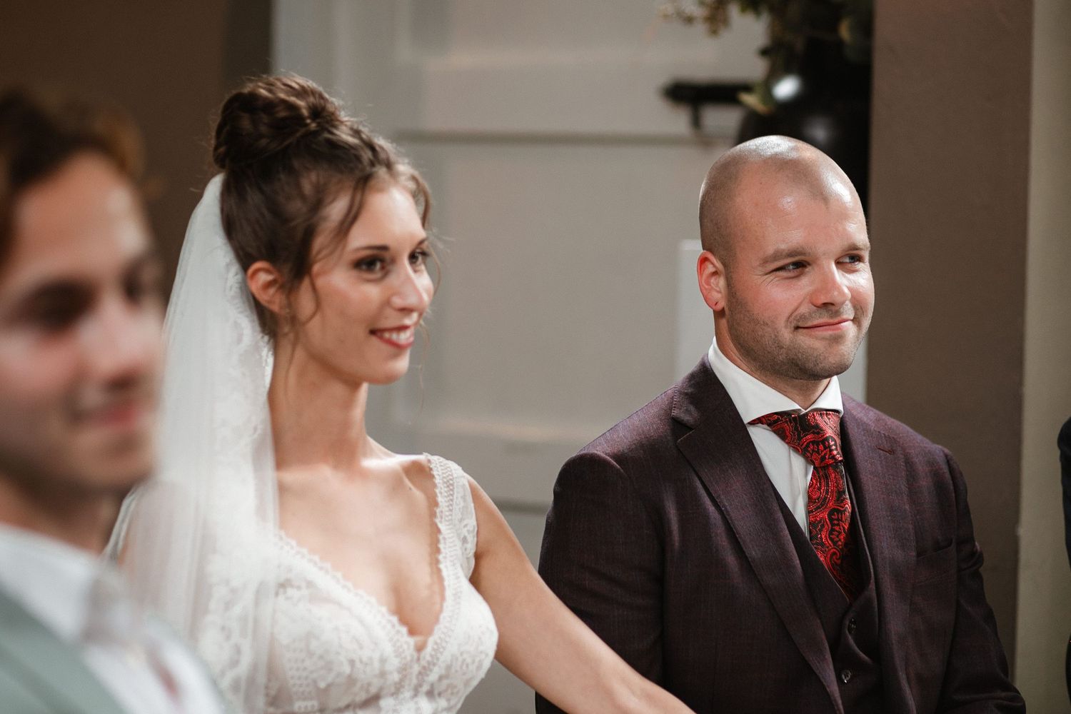 Wedding couple exchanges joyful glances during indoor ceremony.