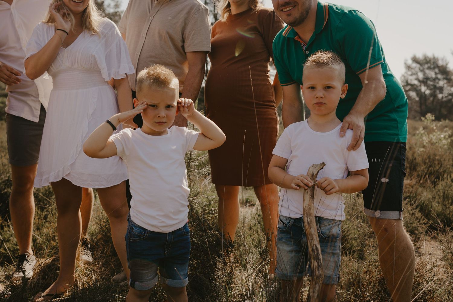 Family group gathered outdoors during sunset in casual attire for a natural photoshoot.