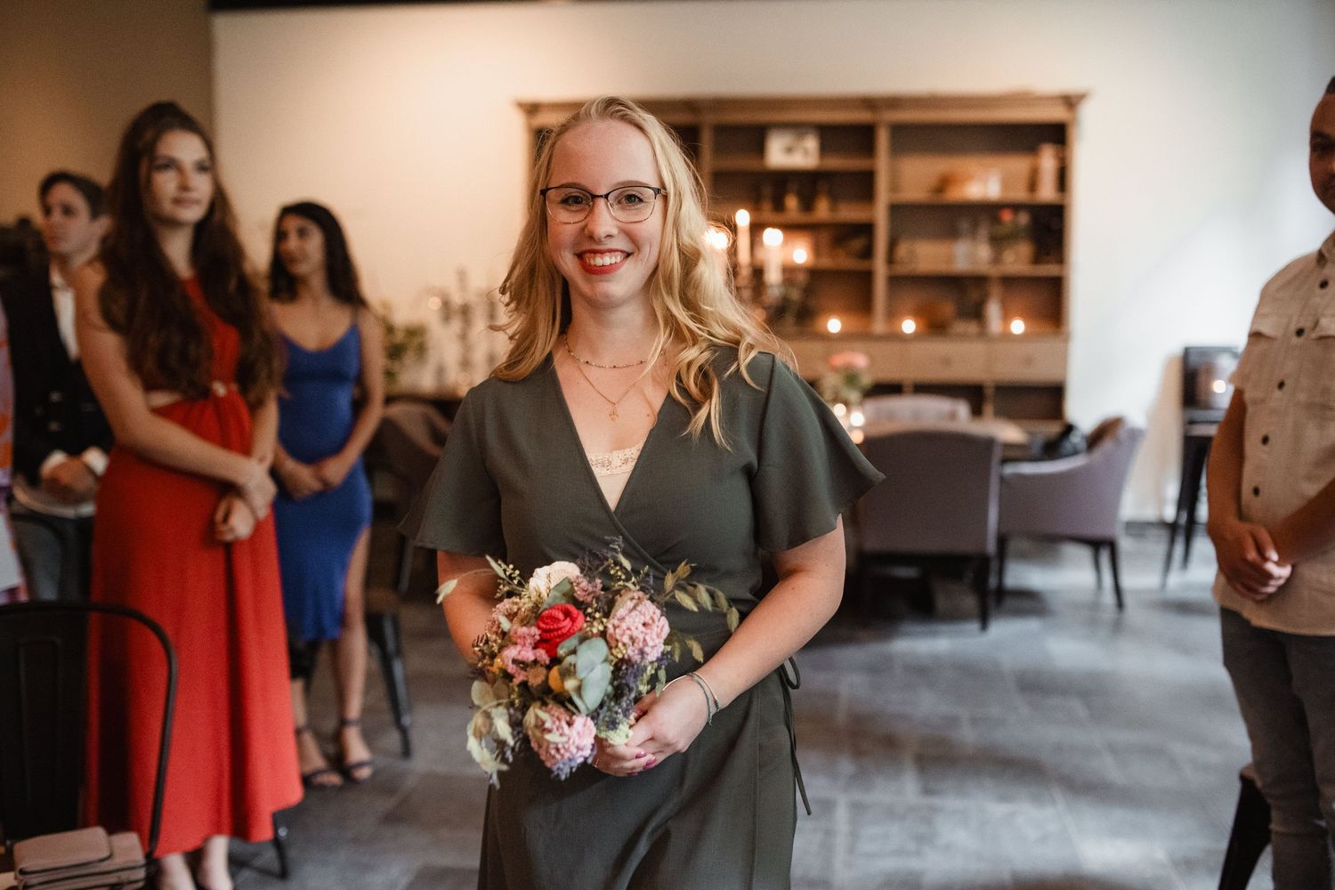 Wedding guests in colorful attire gather to celebrate at an indoor reception venue.