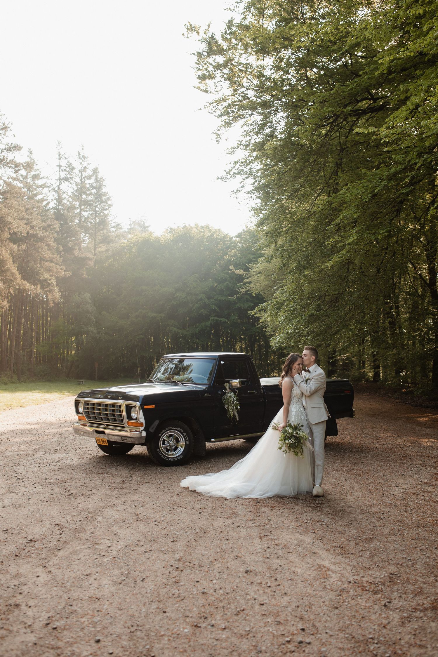 Classic cars frame romantic wedding portraits in a wooded setting.