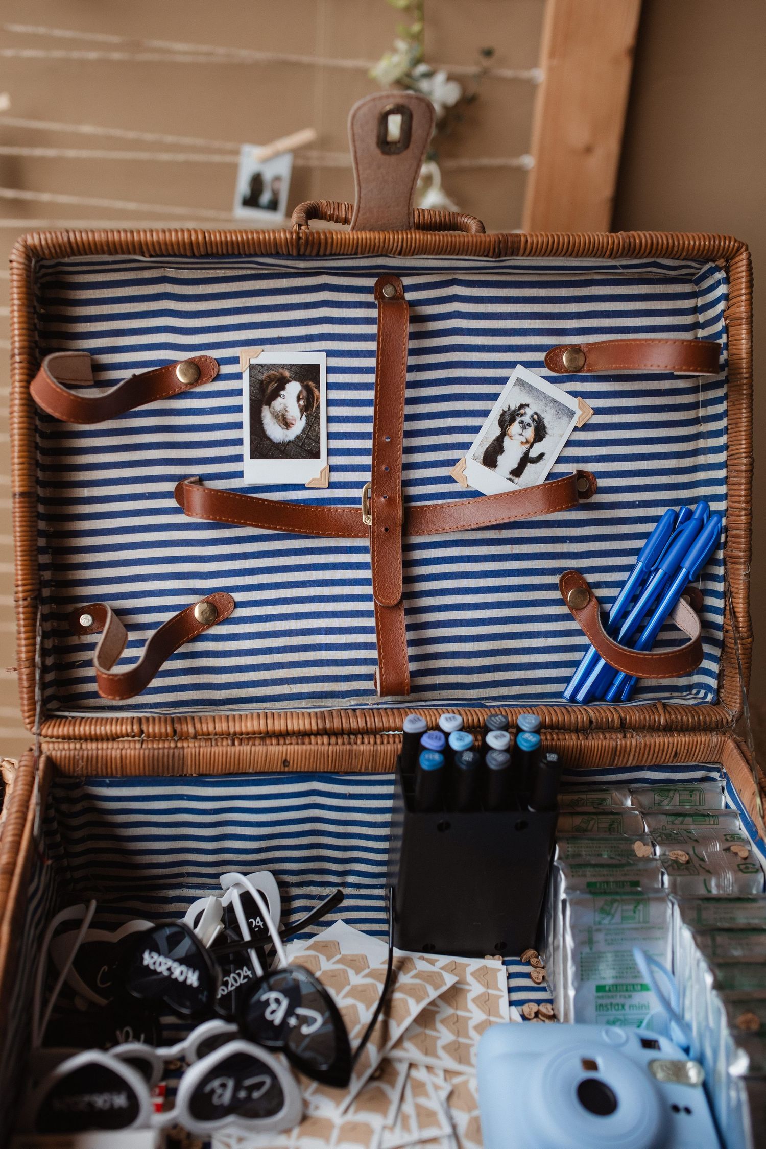 Open vintage suitcase with blue striped lining displaying wedding accessories and decorations.