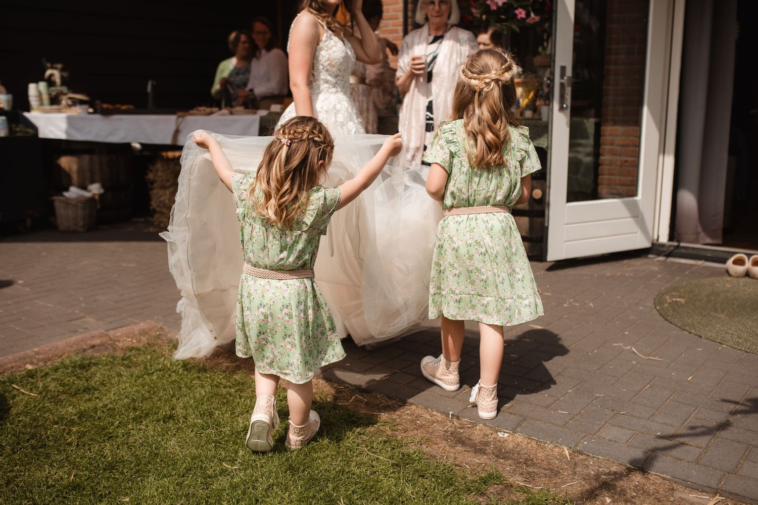 Guests in light summer attire socialize at an outdoor wedding reception.
