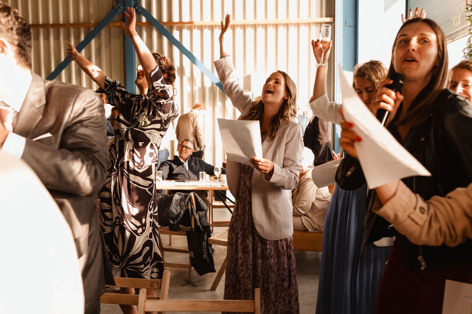 Wedding guests raise their hands in celebration during a festive reception moment.