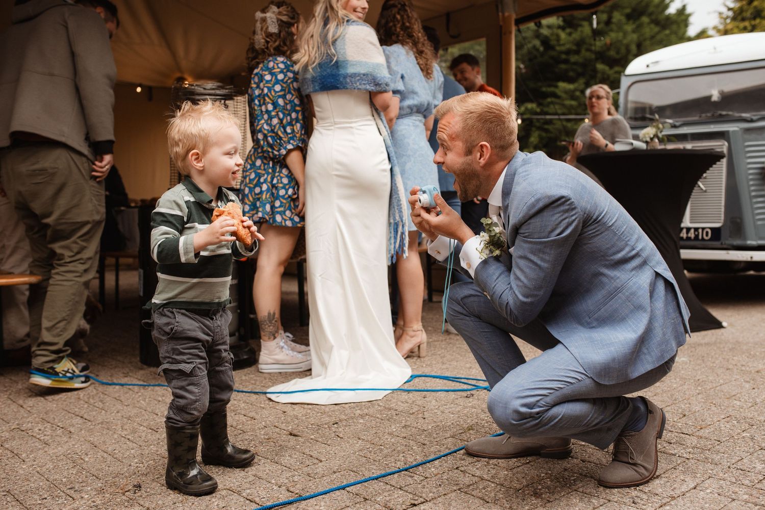 A sweet moment shared between adults and a small child at an outdoor wedding reception.