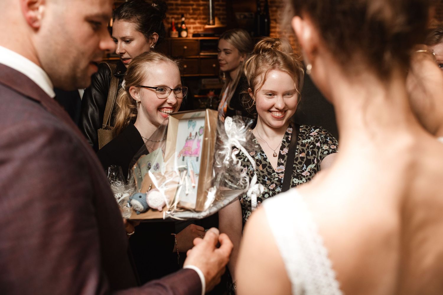Wedding reception guests mingling and celebrating in warm ambient lighting.