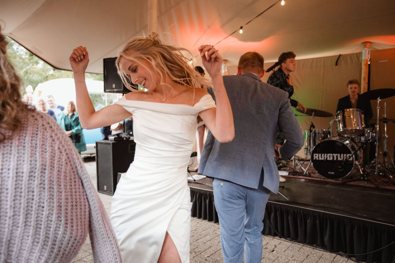 Wedding reception dance party under tent with guests celebrating on dance floor.