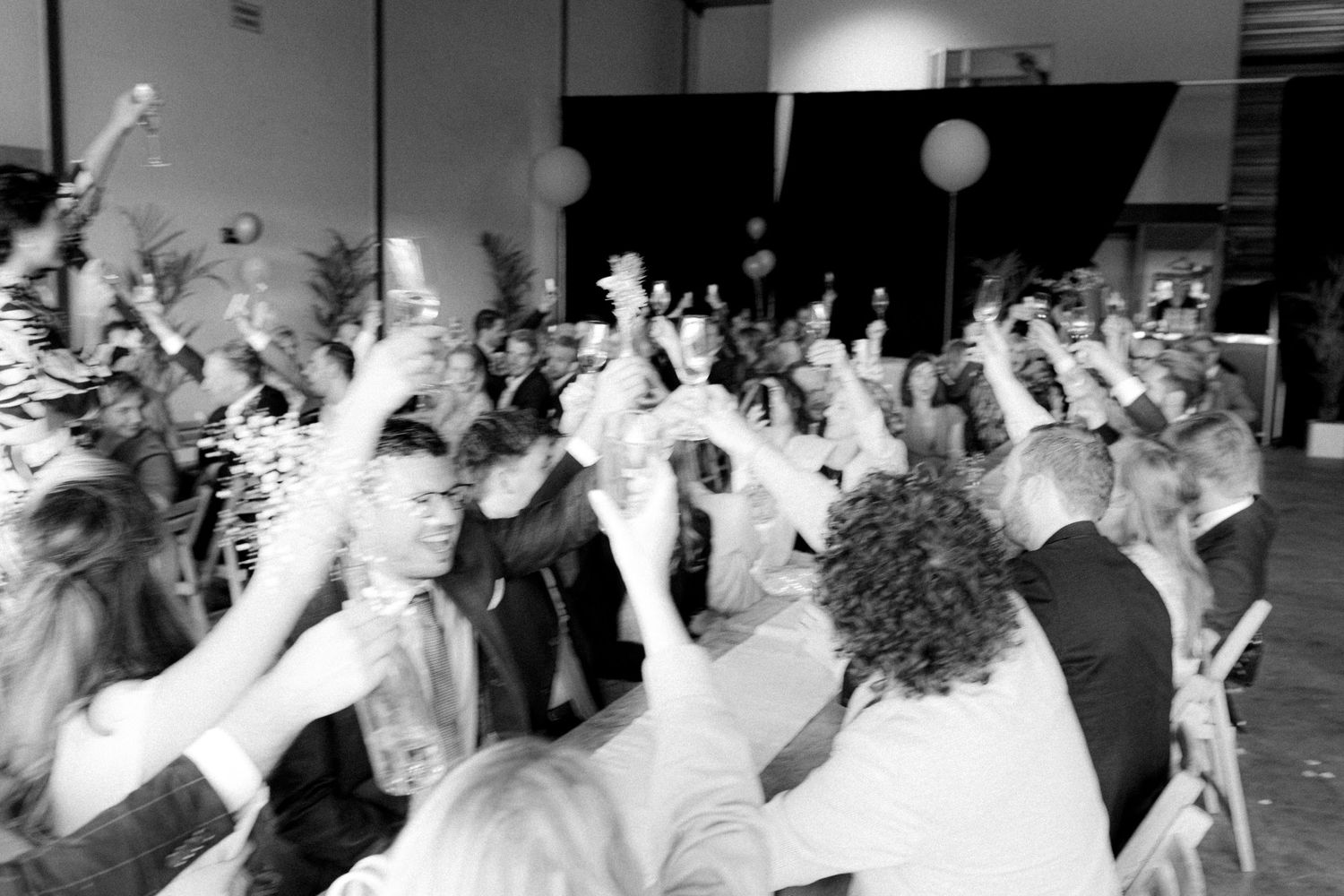Black and white photo captures dancing wedding guests in energetic celebration.