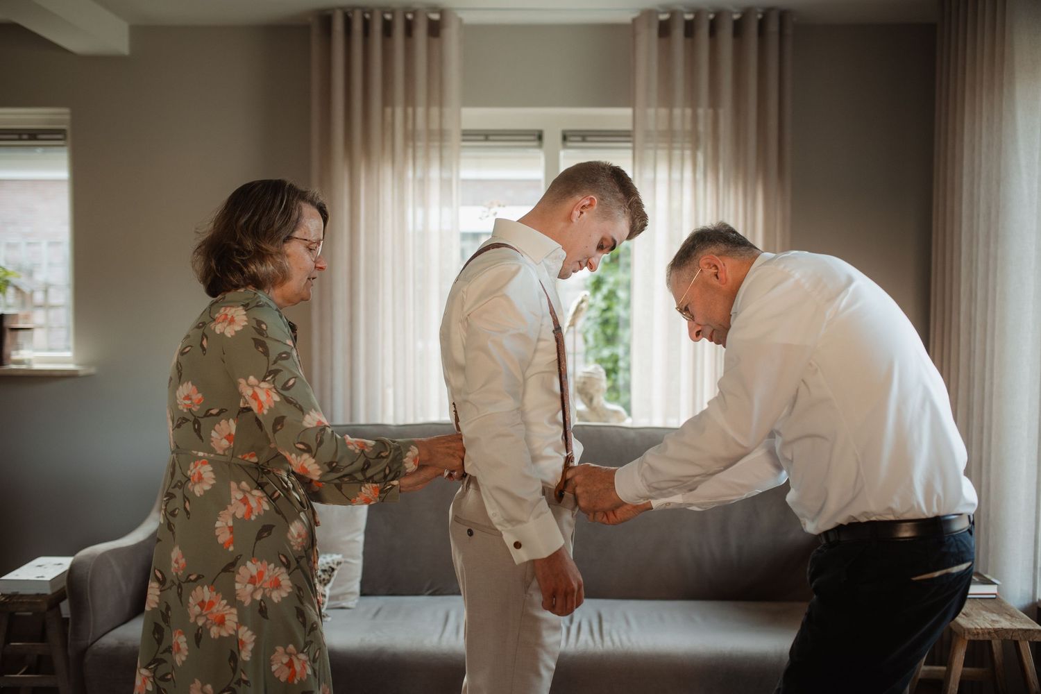 People getting ready in a room with beige curtains and natural lighting.