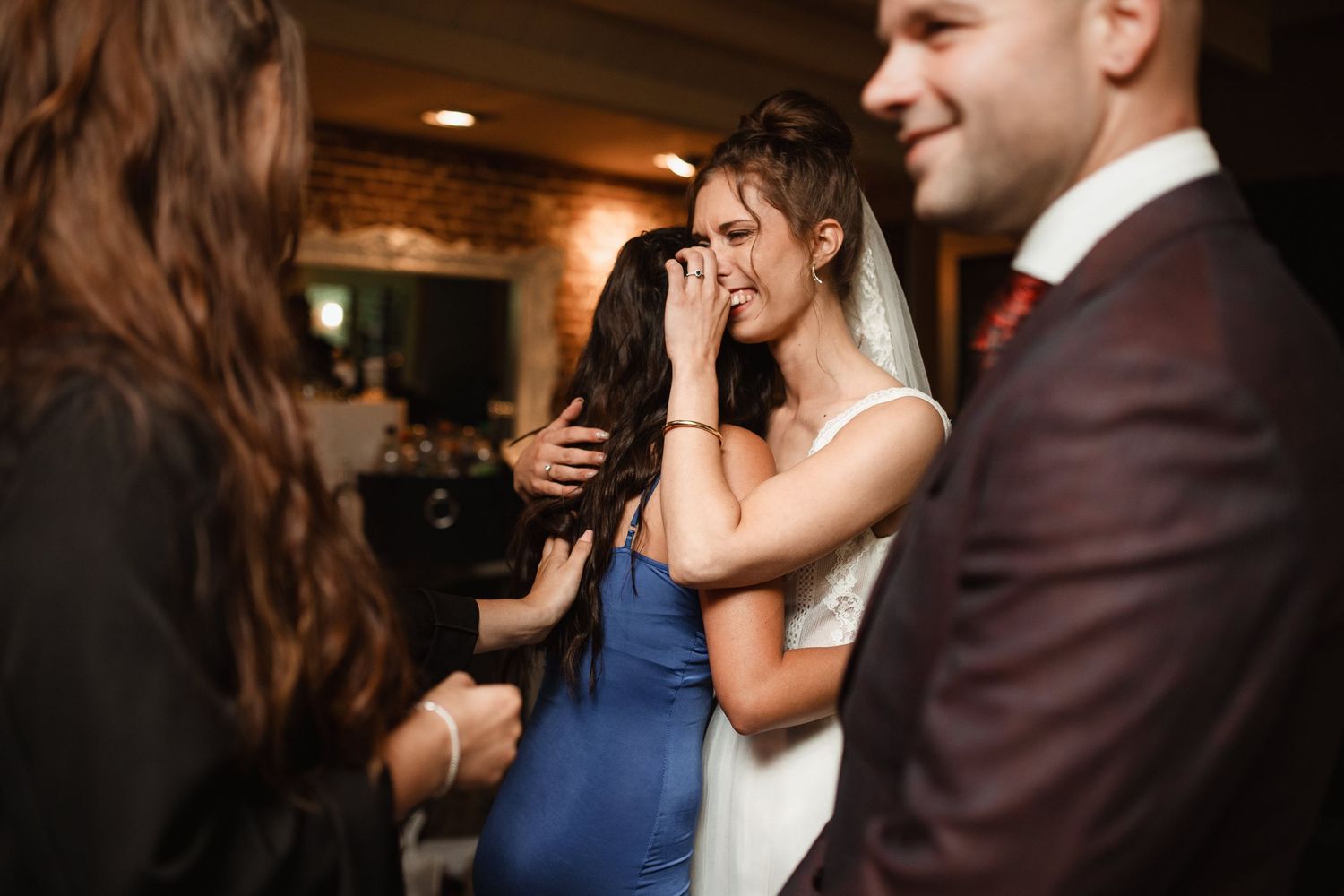 Candid reception moment captured in dark ambient lighting with dancing guests.