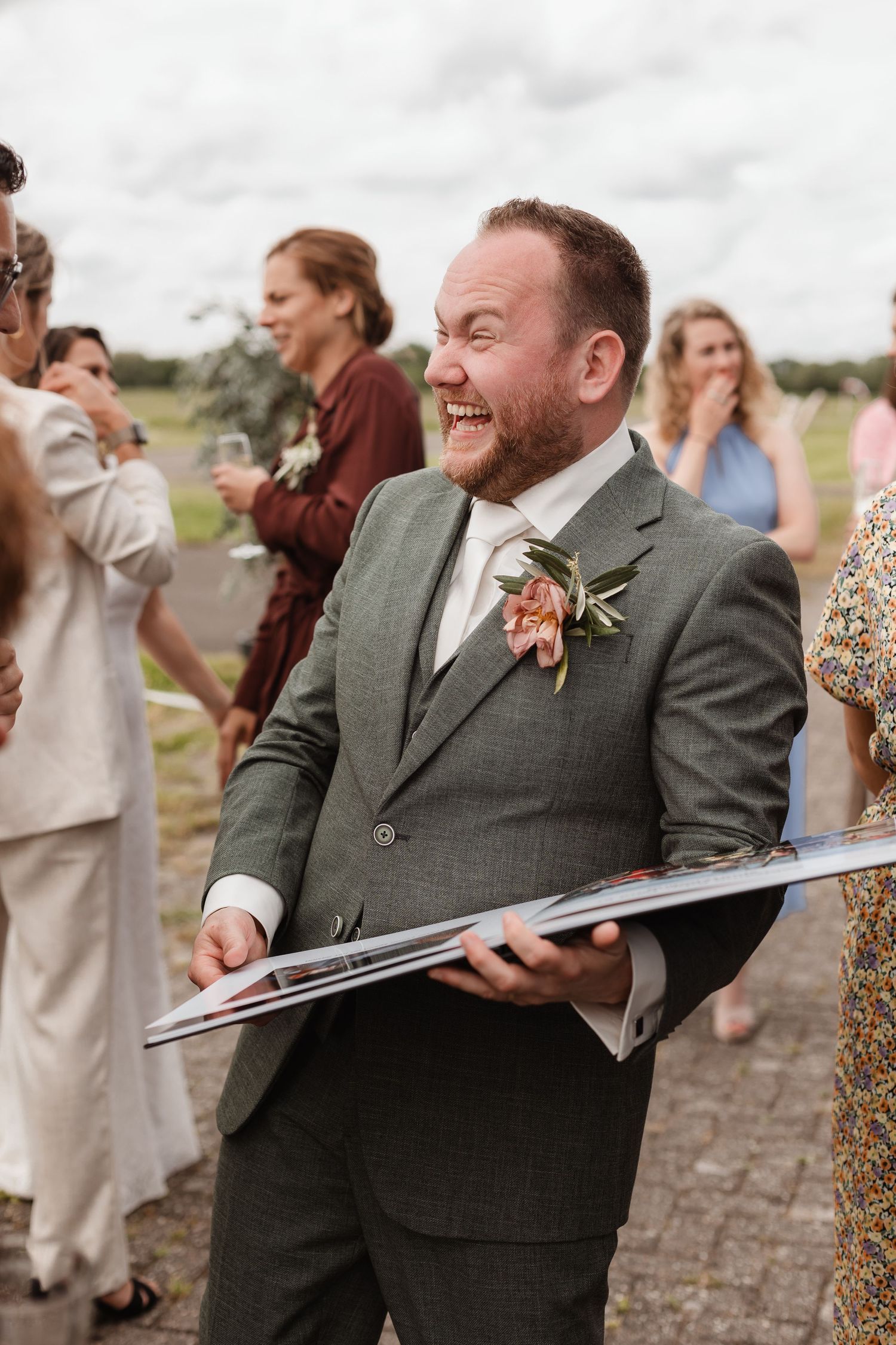 Wedding guests react with laughter and joy during an outdoor ceremony.