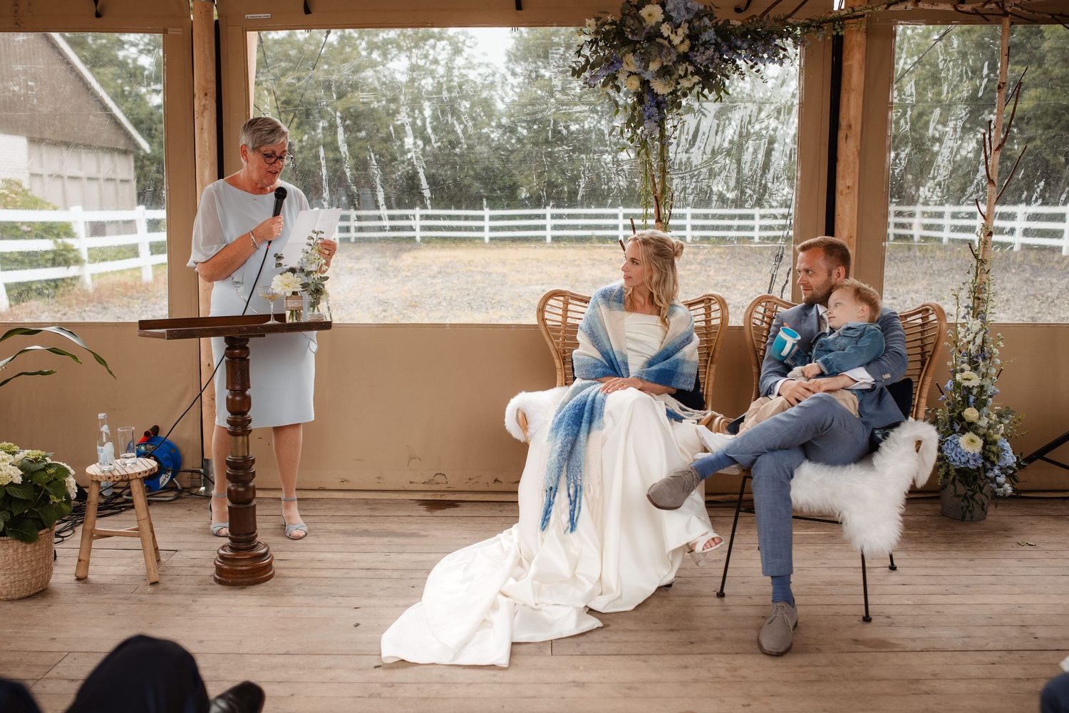 Wedding party enjoying moments together on a covered porch with white fencing in background.