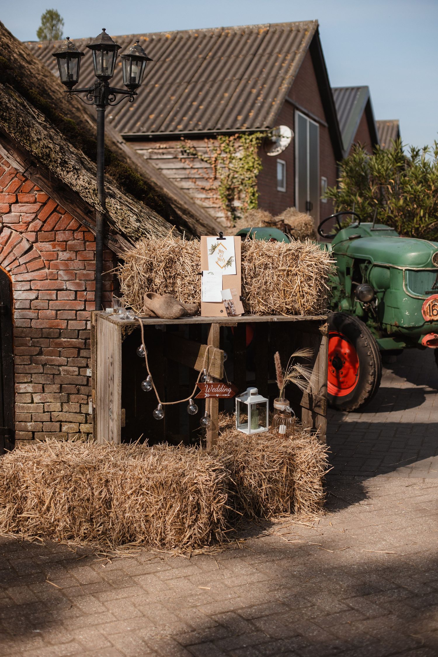 Rustic farm setting with hay bales and brick buildings under blue sky.