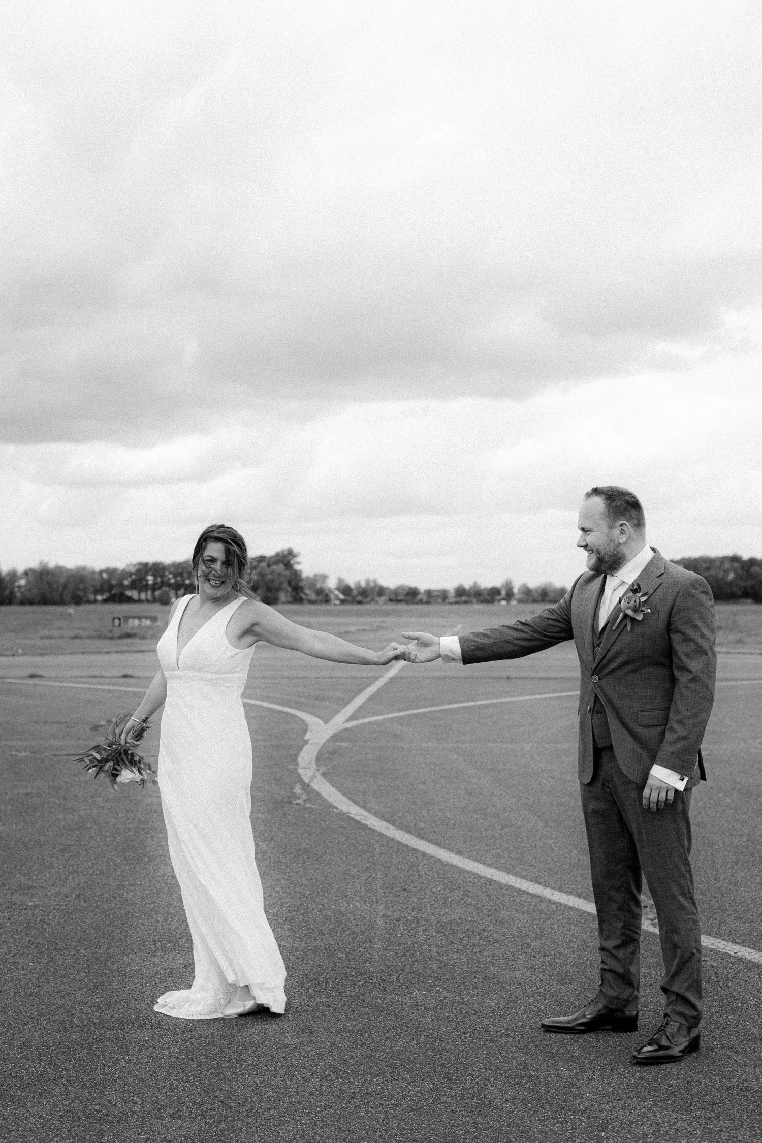 Black and white wedding portraits in open field with winding path.