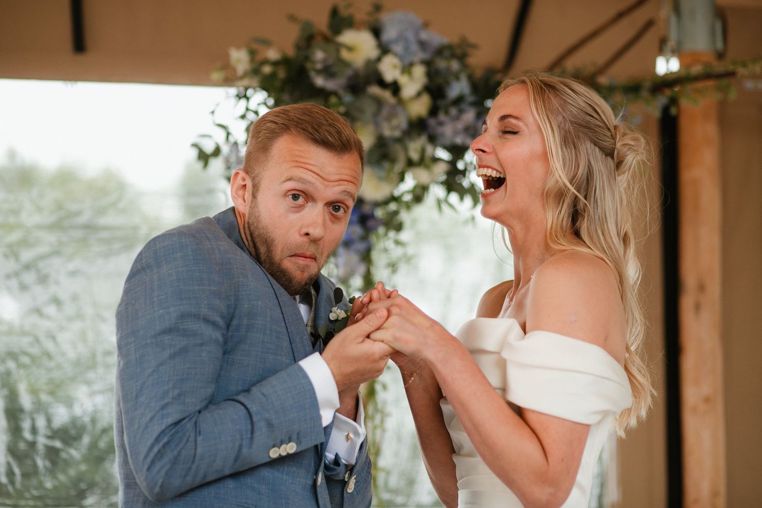 Newlyweds share a joyful dance under a covered pavilion decorated with floral arrangements.