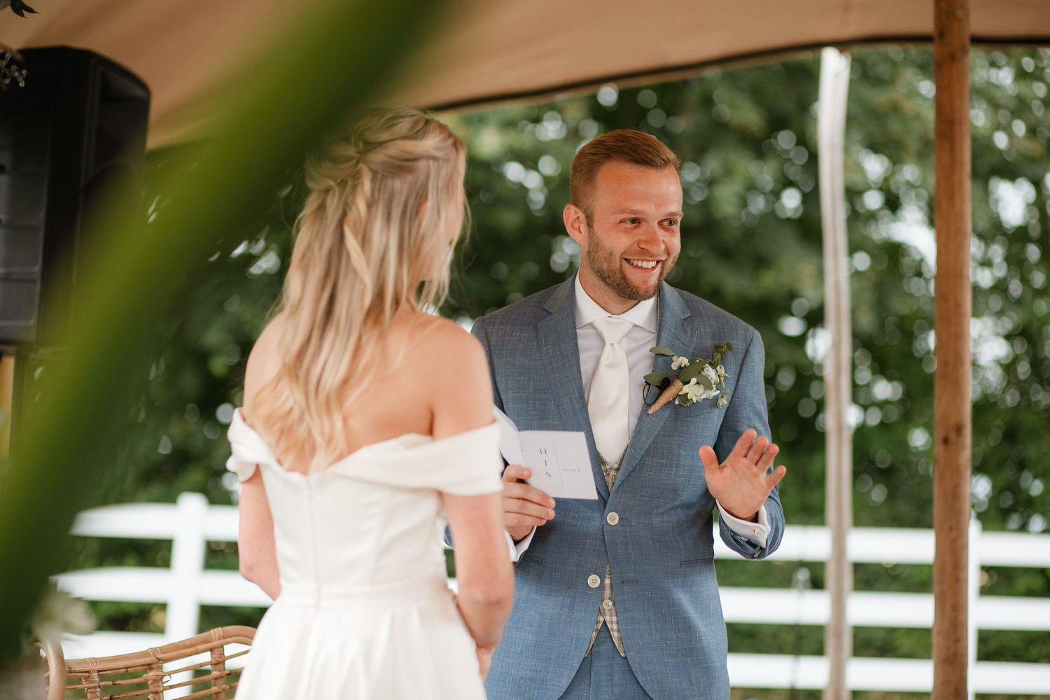 A couple laughs together during a candid moment at their rustic outdoor wedding reception.