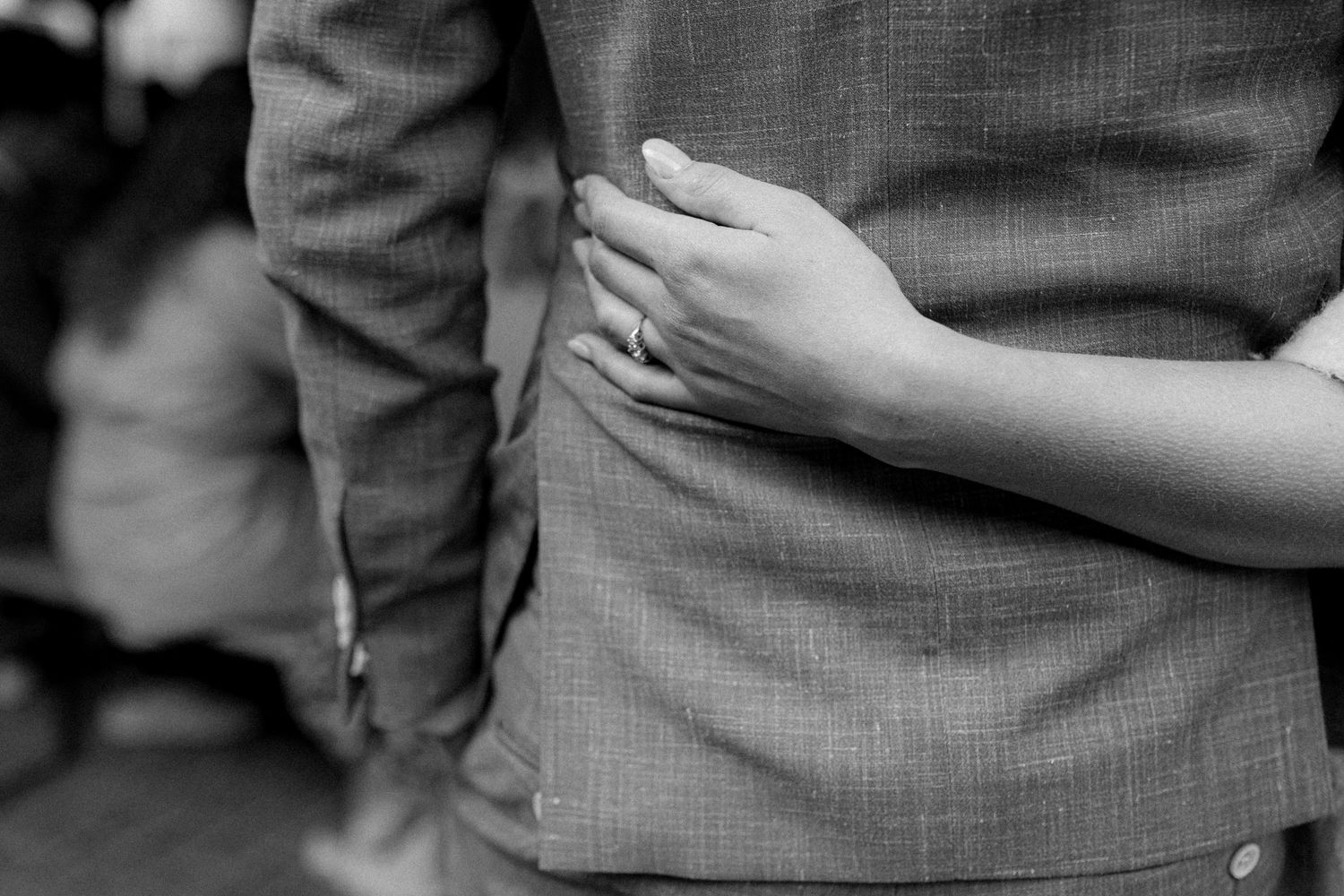 Close-up of hands embracing around waist in formal attire.