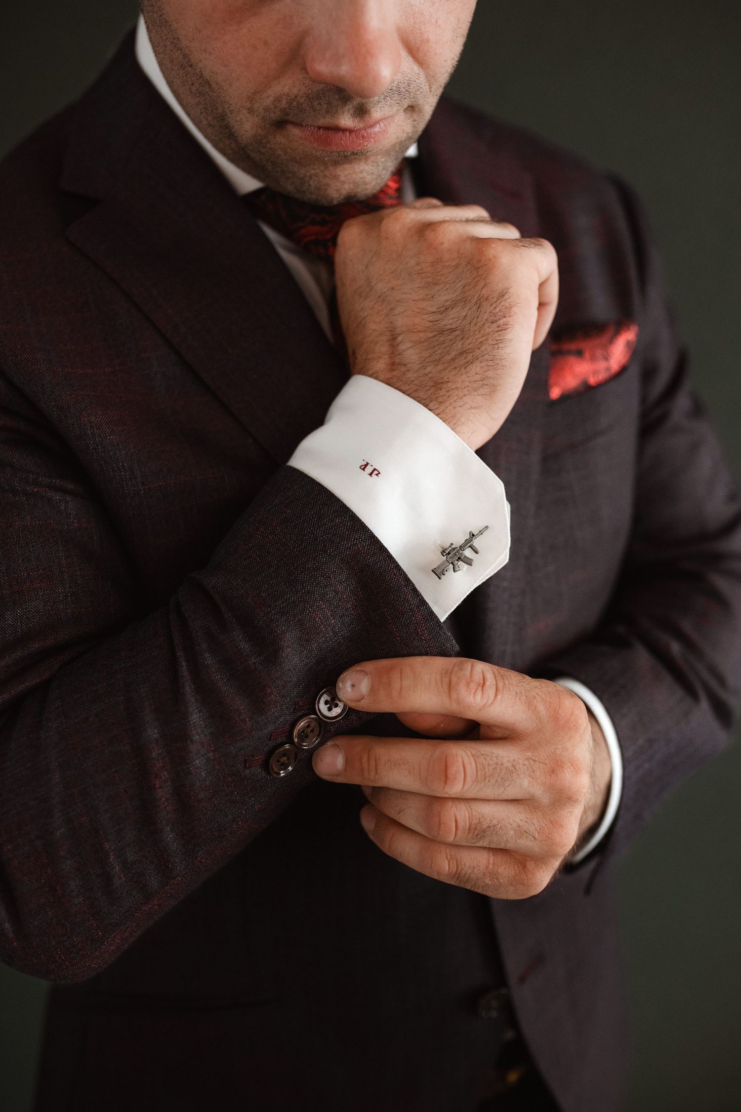 Close-up detail shot of a groom adjusting his suit cuff link.