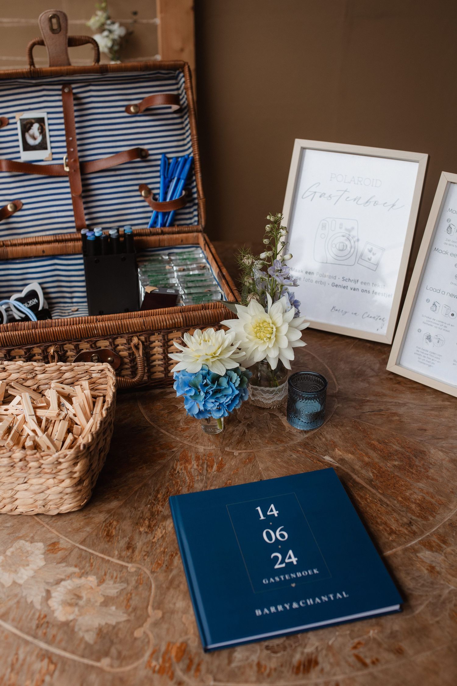 Wedding details including a vintage suitcase, blue flowers, and date book on wooden surface.