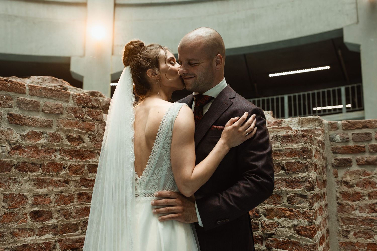 A romantic moment between newlyweds in an industrial-style venue with exposed brick walls.