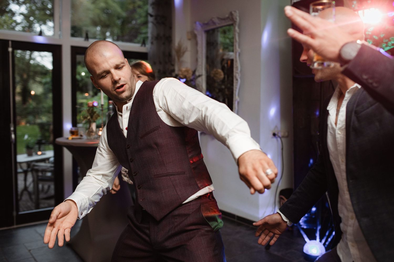 People dancing energetically at a wedding reception in formal attire.