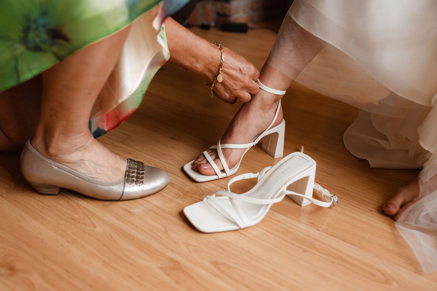 Various wedding shoes and footwear arranged on a wooden floor.