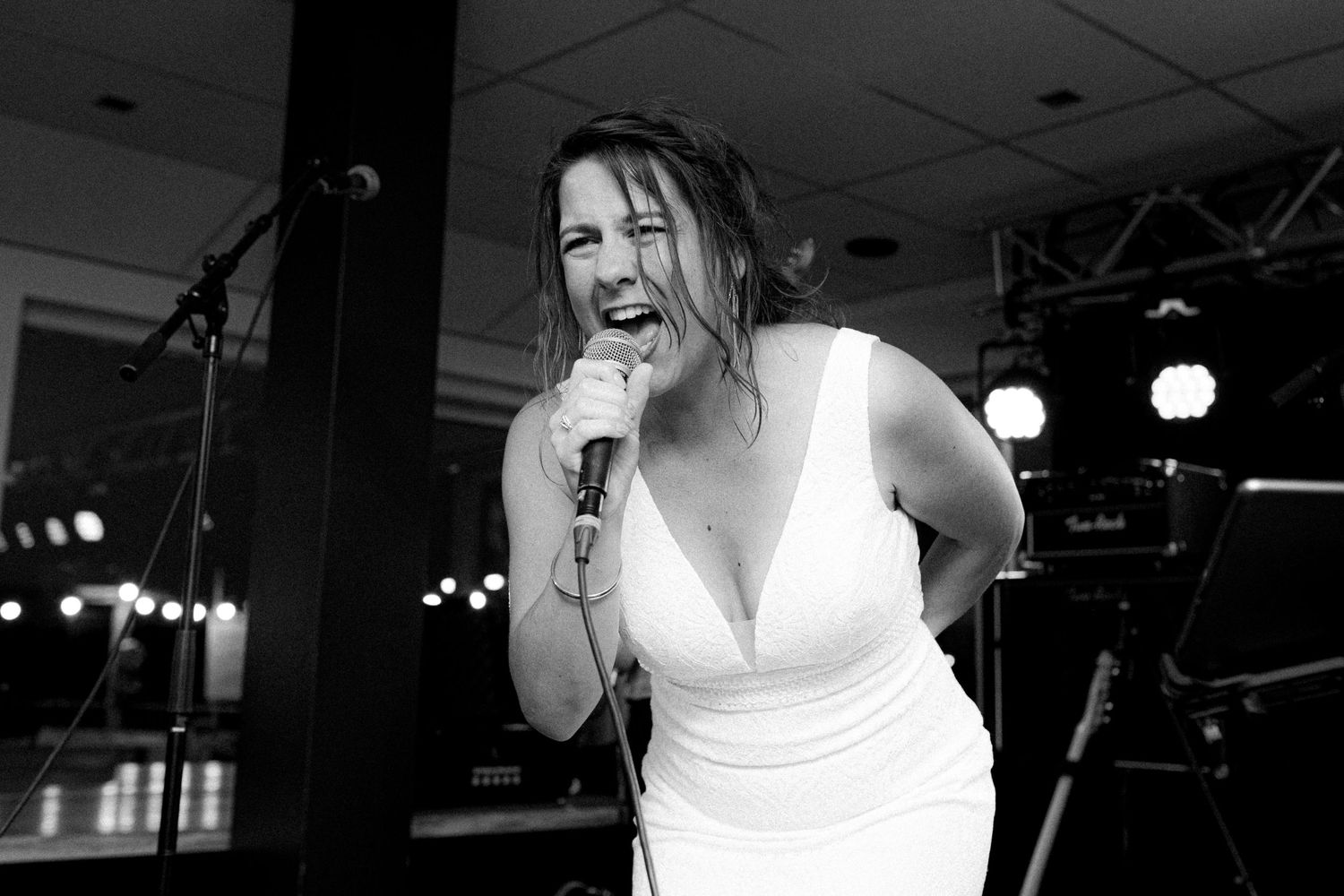 Monochrome image of people dancing and laughing in a dark venue with stage lighting.
