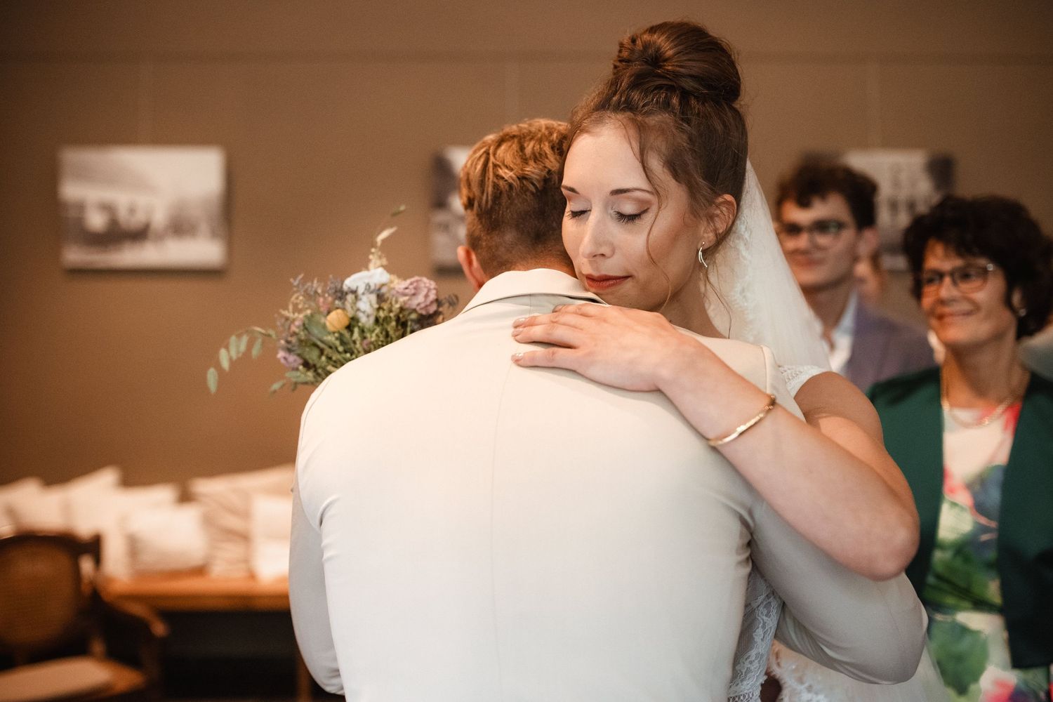 Emotional wedding ceremony moment with guests watching as couple embraces in a warm hug.
