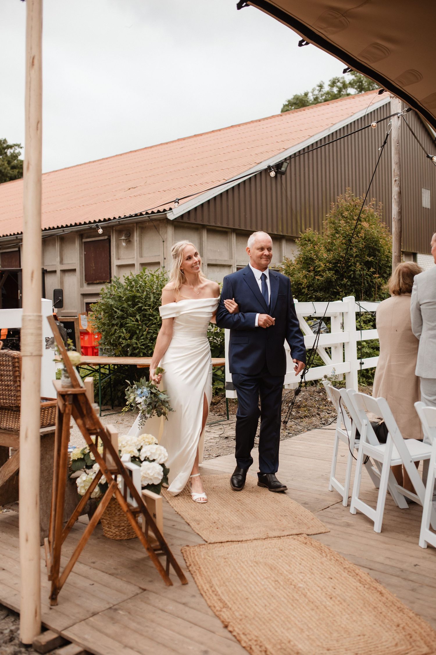 Guests mingling on a covered wooden deck at a rustic wedding venue.