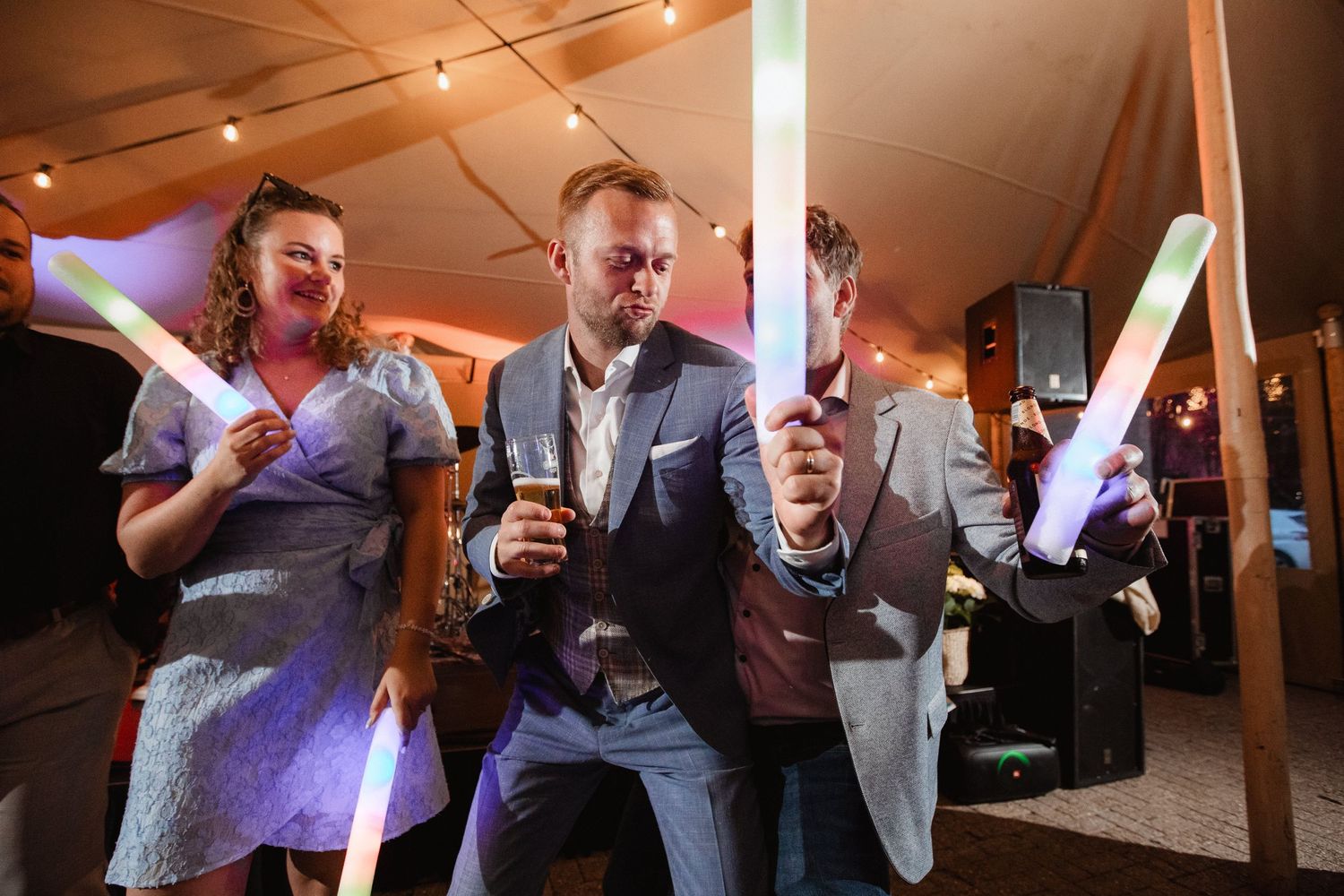 Wedding guests enjoying drinks and conversation under warm reception lighting.