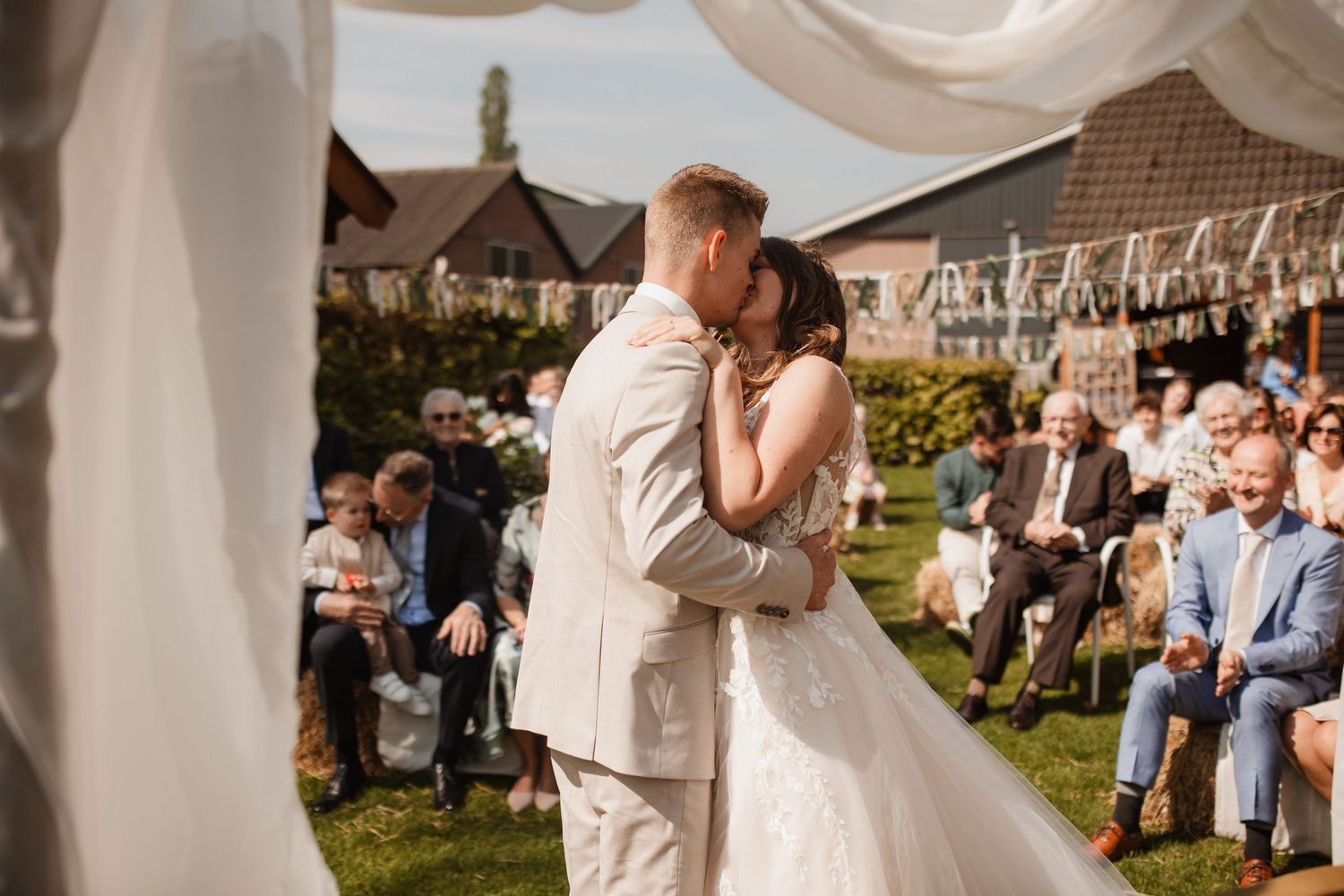 Guests gather under white bunting decorations at an outdoor garden party.