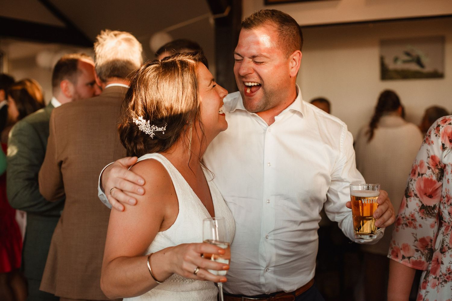 Reception guests share intimate moments of laughter and celebration at evening wedding party.