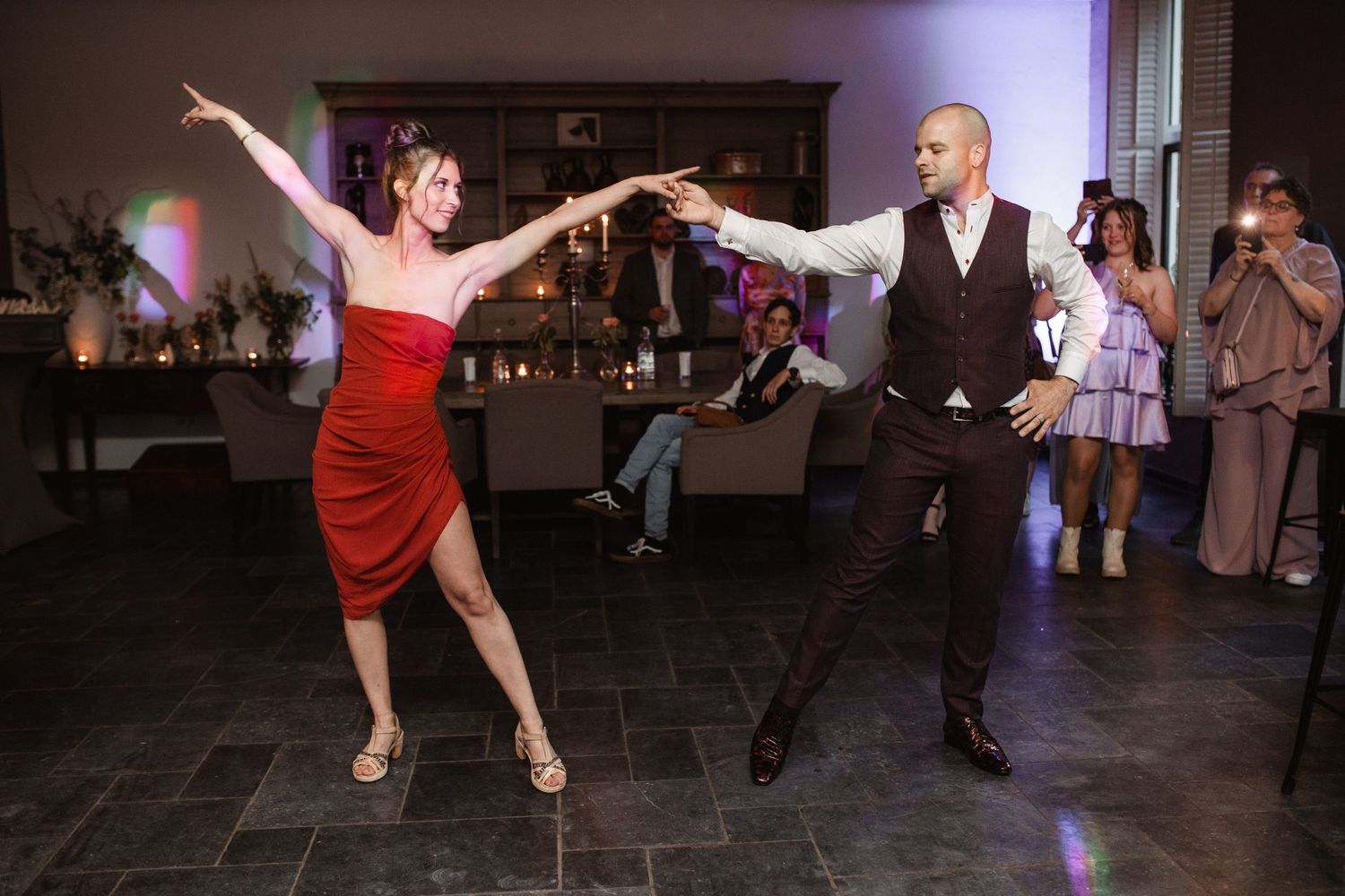 Energetic dancing and celebrations on a dimly lit reception dance floor.